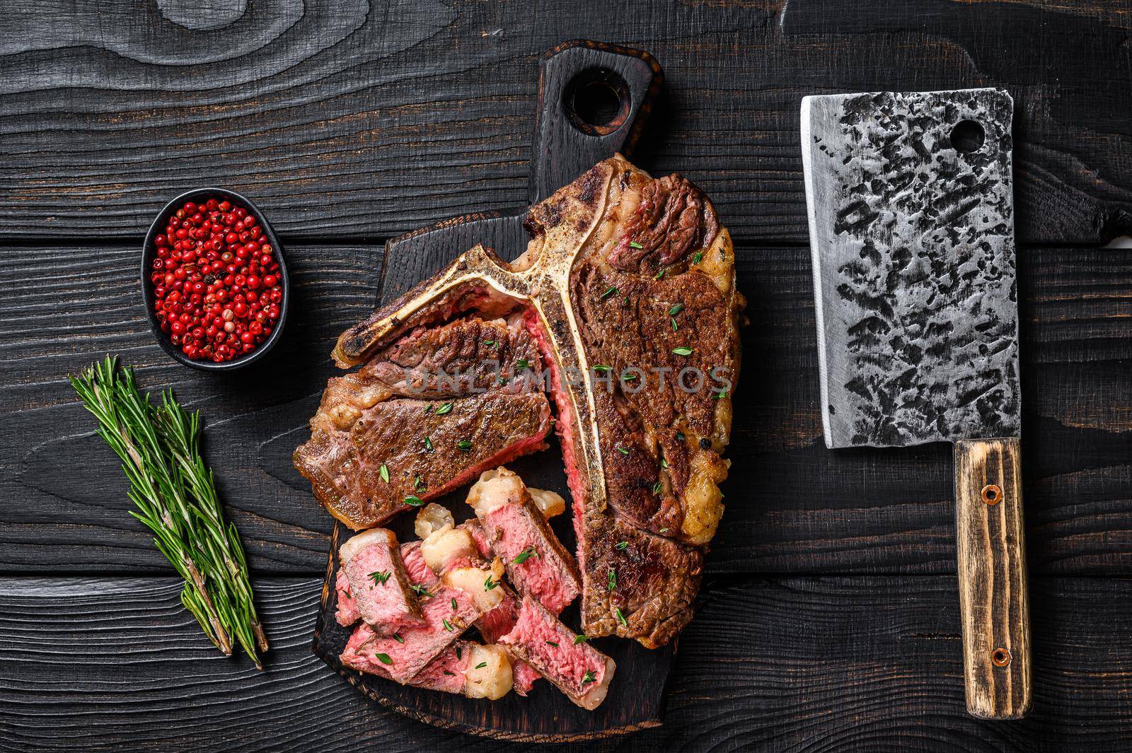 Sliced and roast T-bone or porterhouse beef meat Steak for steakhouse menu. Black wooden background. Top view.