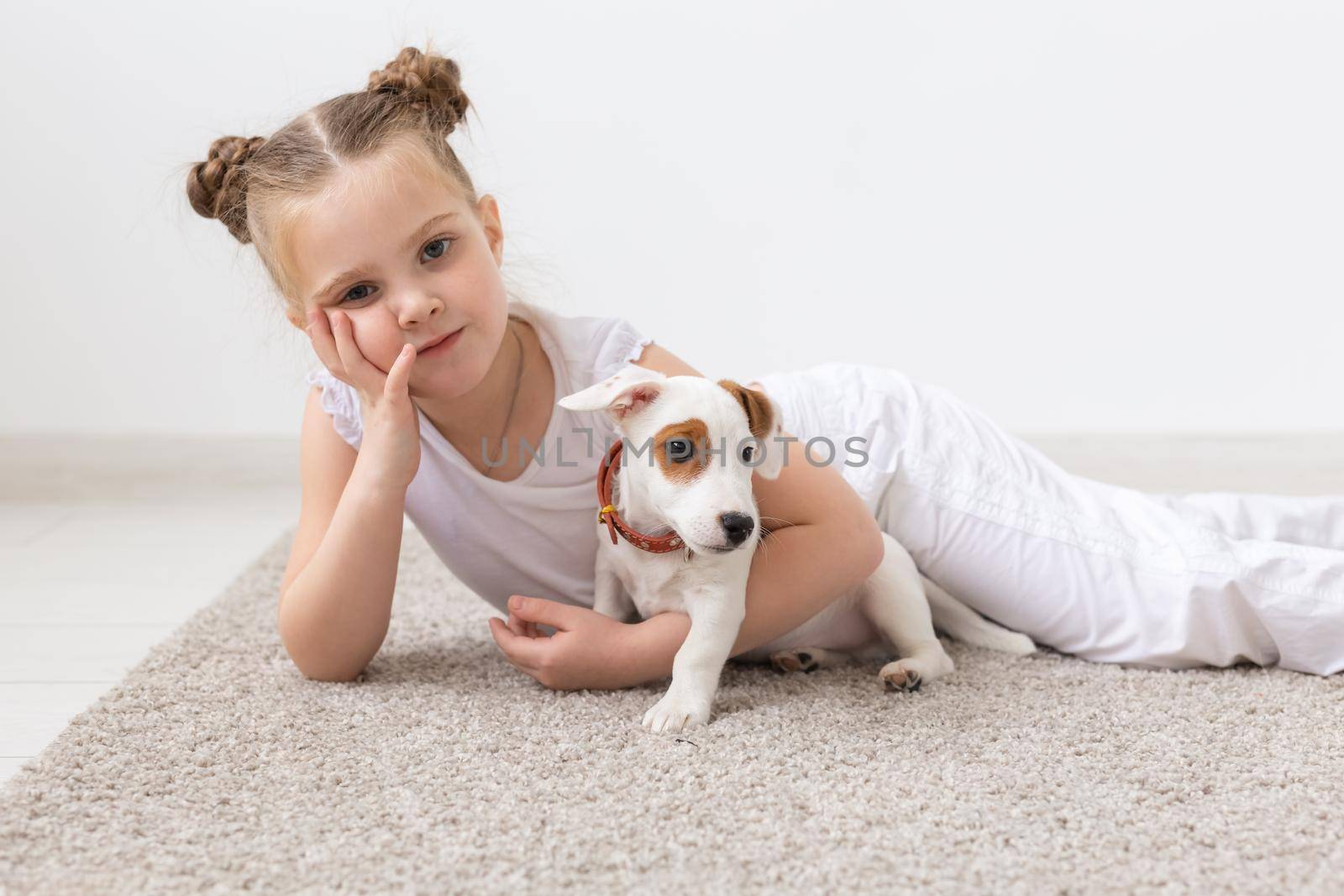 Childhood, pets and dogs concept - Little child girl posing on the floor with puppy.