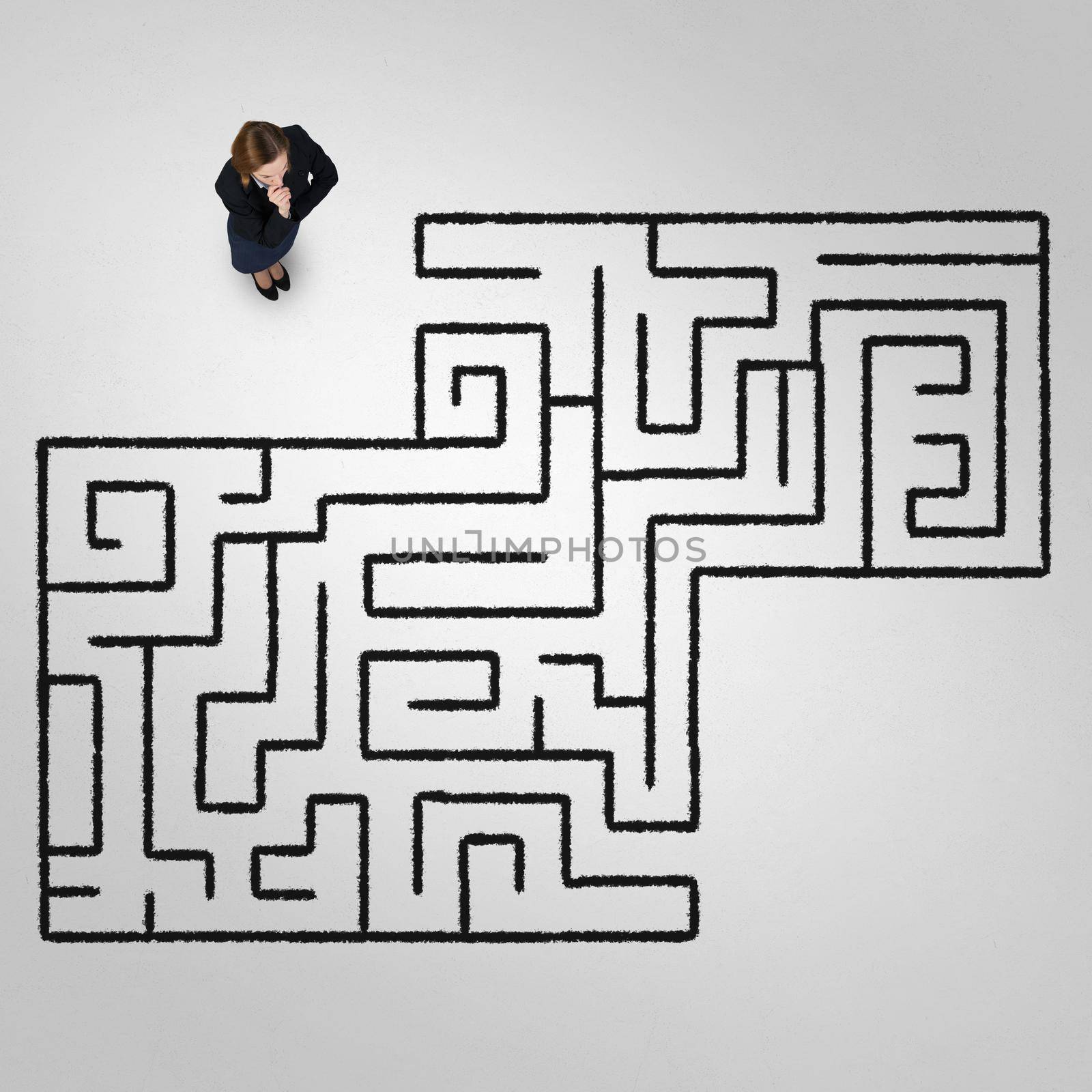 Top view of puzzled businesswoman looking at drawn maze on floor