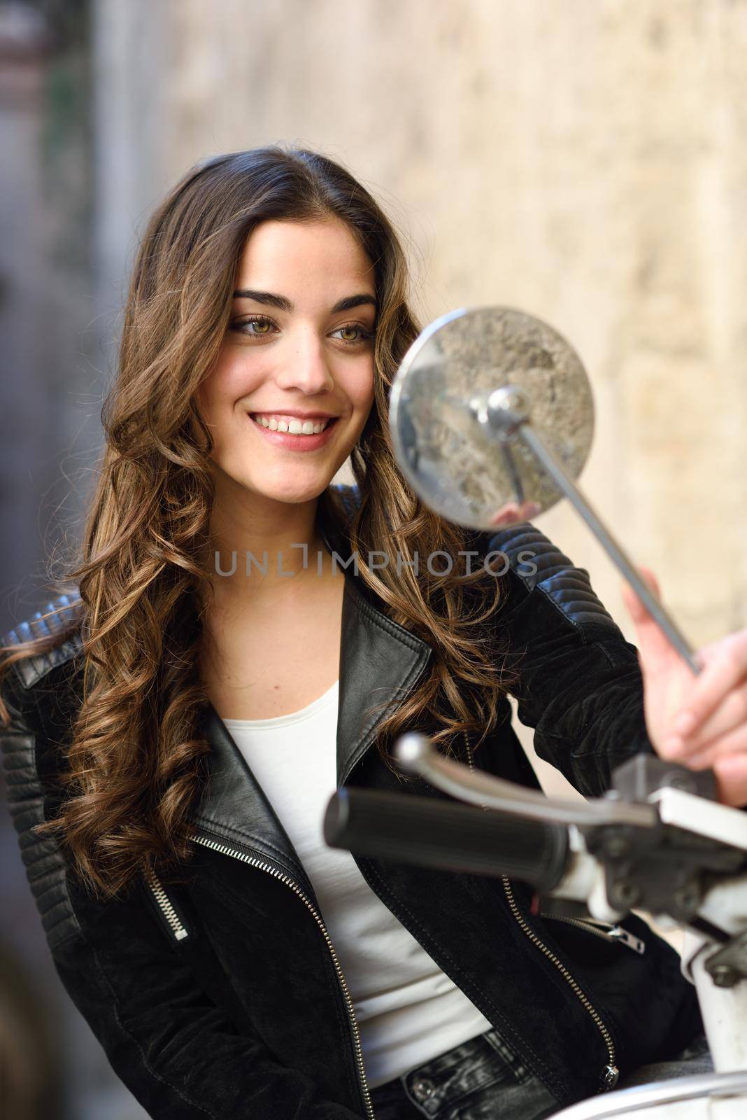 Woman looking in a motorbike's mirror, smiling and wearing casual clothes
