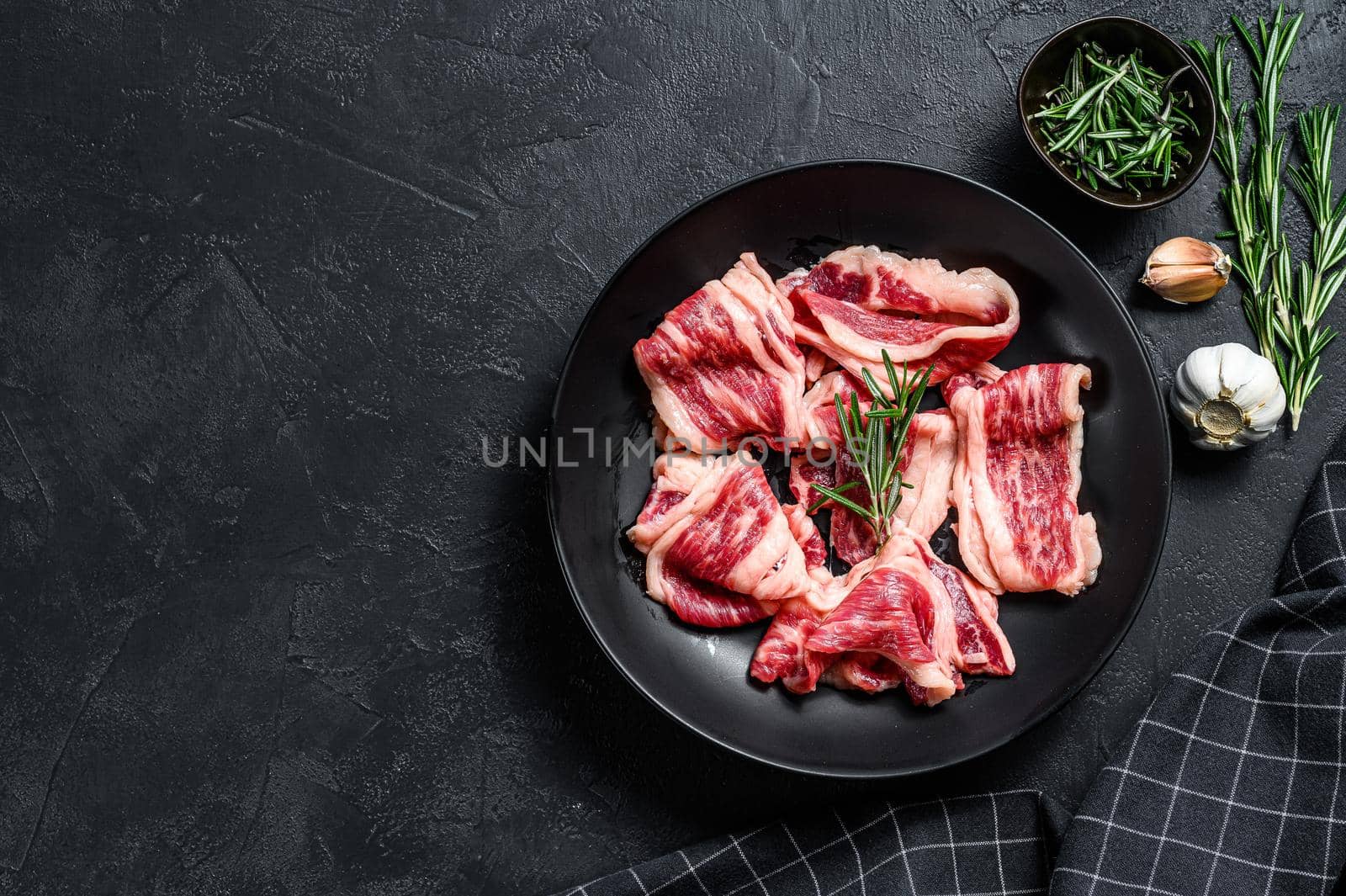 Strips of marbled beef, quick steak. Black background. Top view. Copy space.