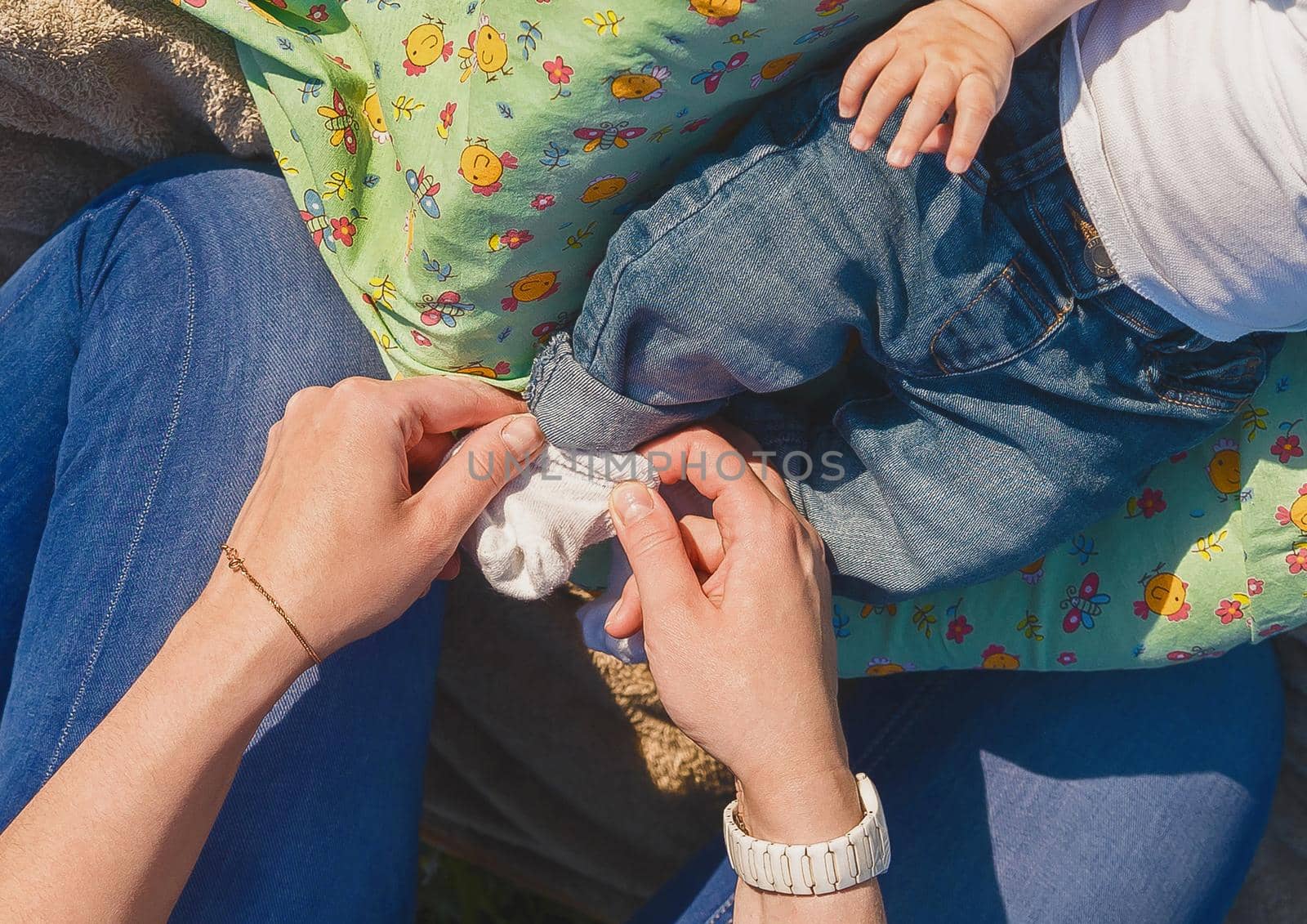 Mom's hands put on socks on the baby's feet, close up.