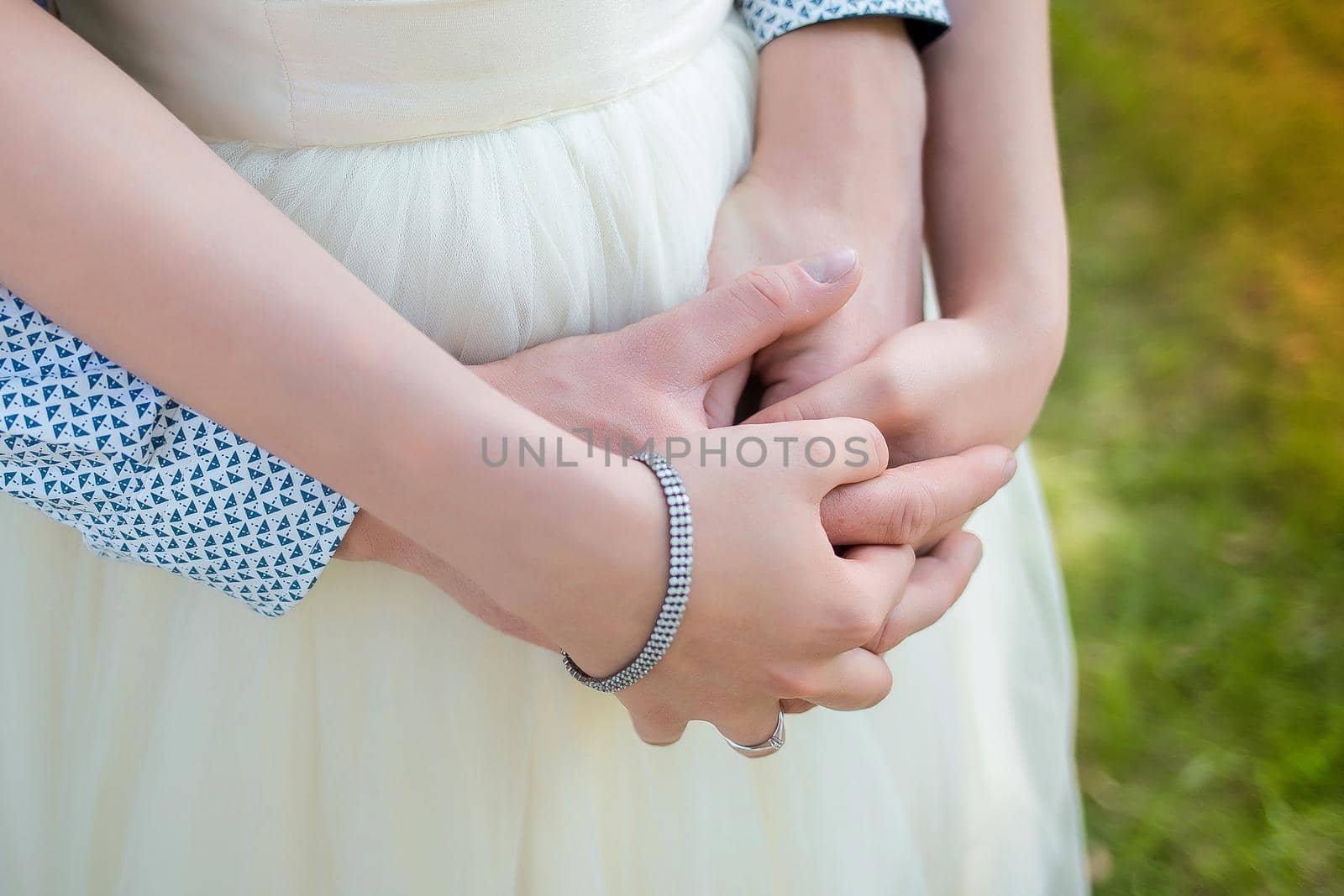 Men's and women's hugs. The guy's hands are held by the girl's arms from behind. Romantic relationships.