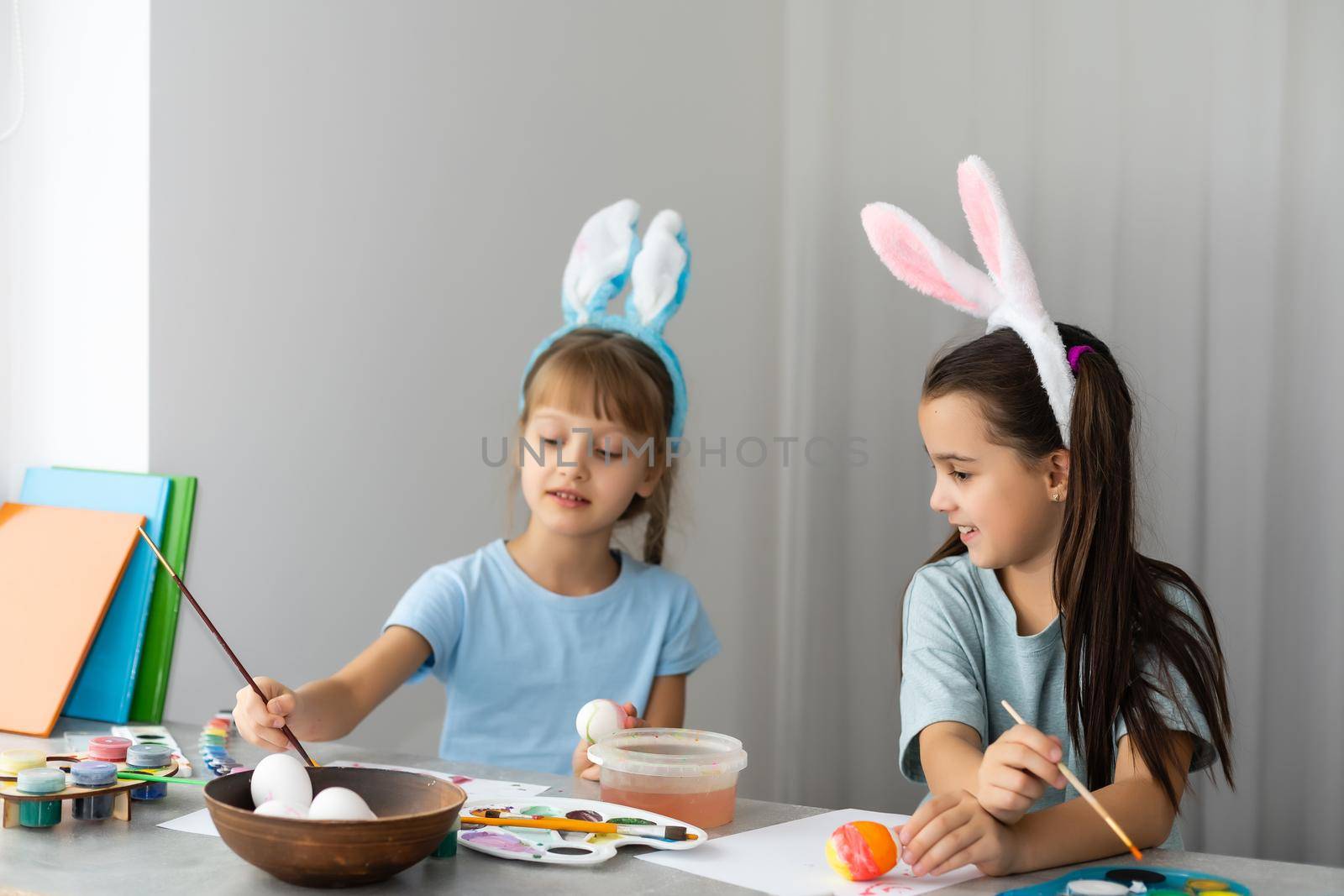 Two little cute girls painting on Easter eggs