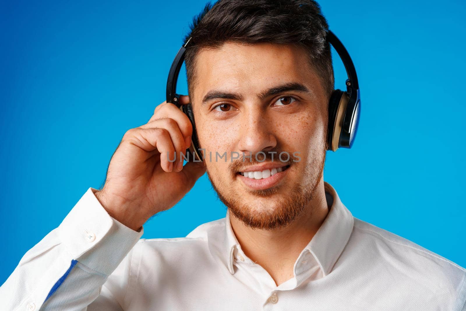 Handsome young mixed-race man listening to music with blue headphones close up