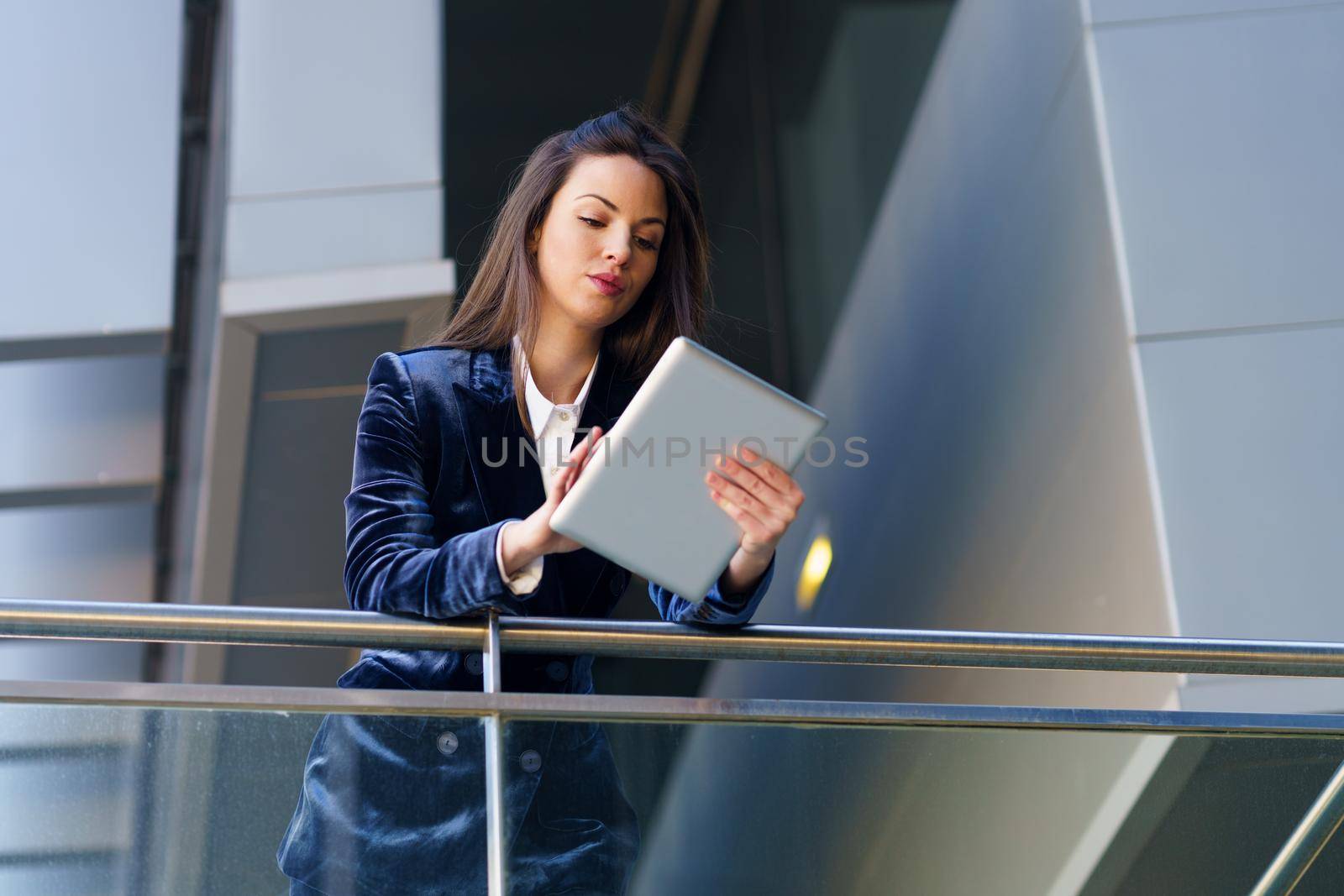 Business woman wearing blue suit using digital tablet in an office building. Lifestyle concept.