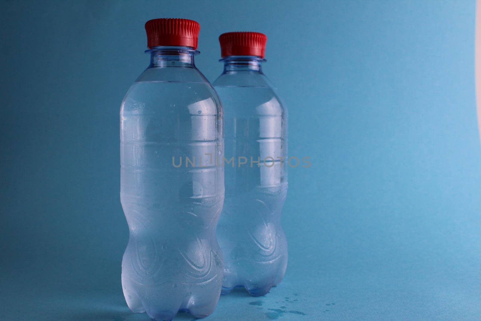 Drinking mineralated water in plastic bottles on a blue background with a place for text and with a copypispe. pure water. Cold soft drinks. Refreshing by Shoba