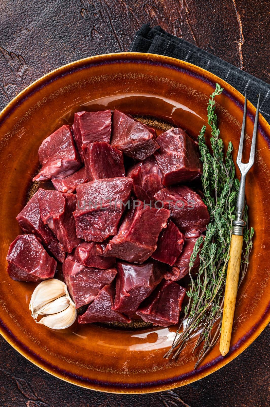 Cut Beef or veal raw heart in a rustic plate with herbs. Dark background. Top View by Composter