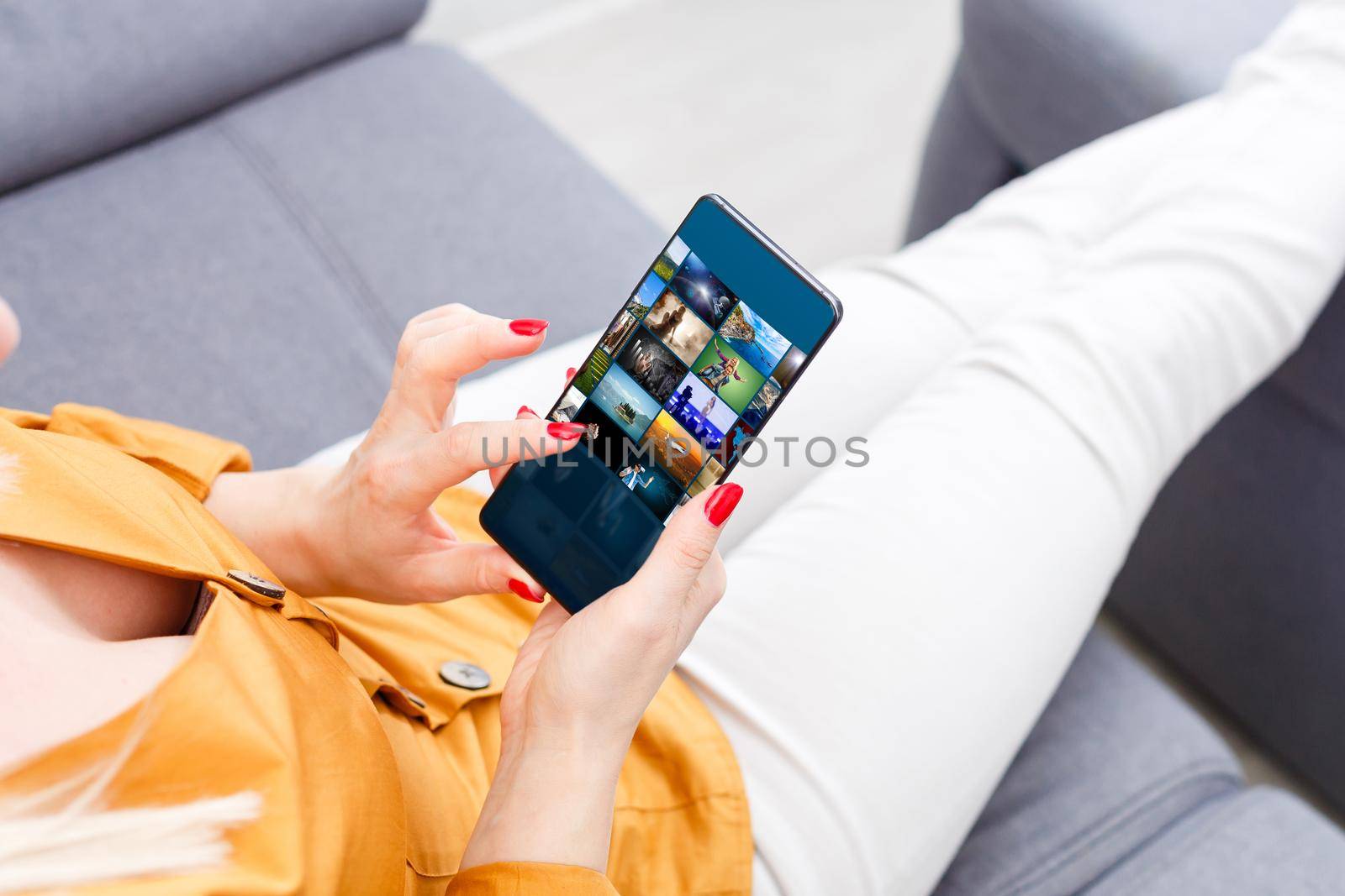 Closely image of female hands holding mobile phone with photo camera mode on the screen. Cropped image of hipster girl watching video