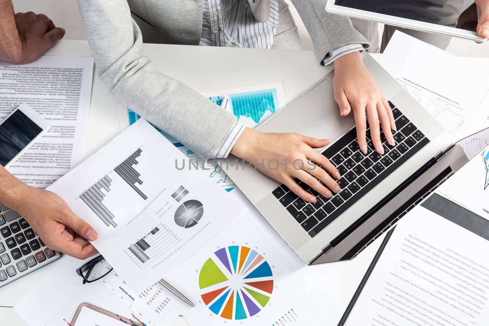Business team working with documents. Secretary typing on laptop computer. Office desk with financial charts. Analysis of investment attractiveness and profit calculation. Business meeting in office