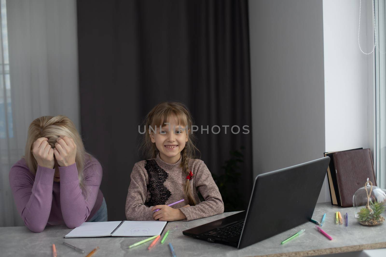 Woman with girl doing homework on laptop by Andelov13