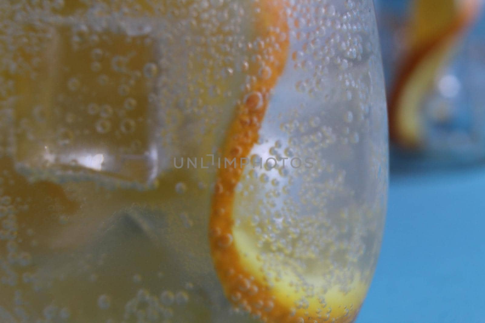 Lemonade water divorcing in a glass of ice and orange is very close-up. Macrophoto.