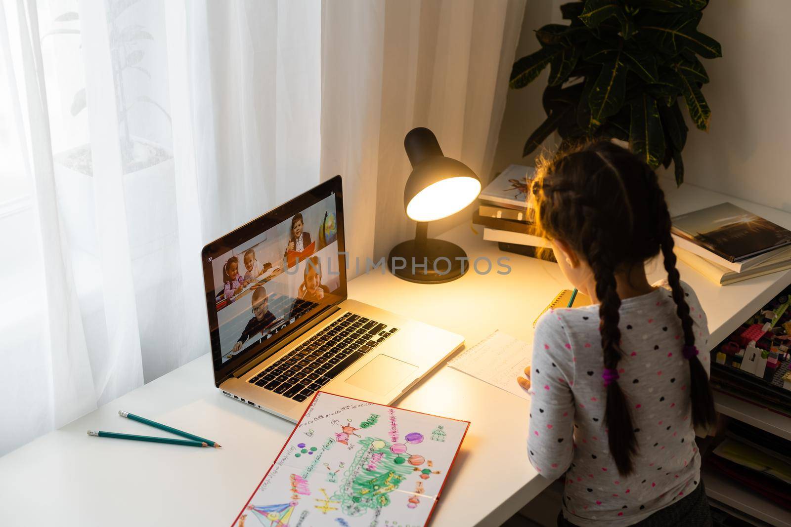 Little girl studying online using her laptop at home