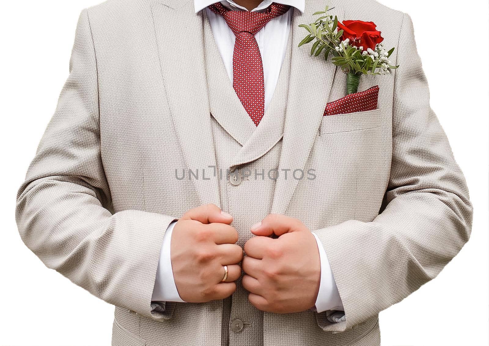 The groom's light beige suit holds hands with a boutonniere and a red tie isolated white background close-up by AYDO8