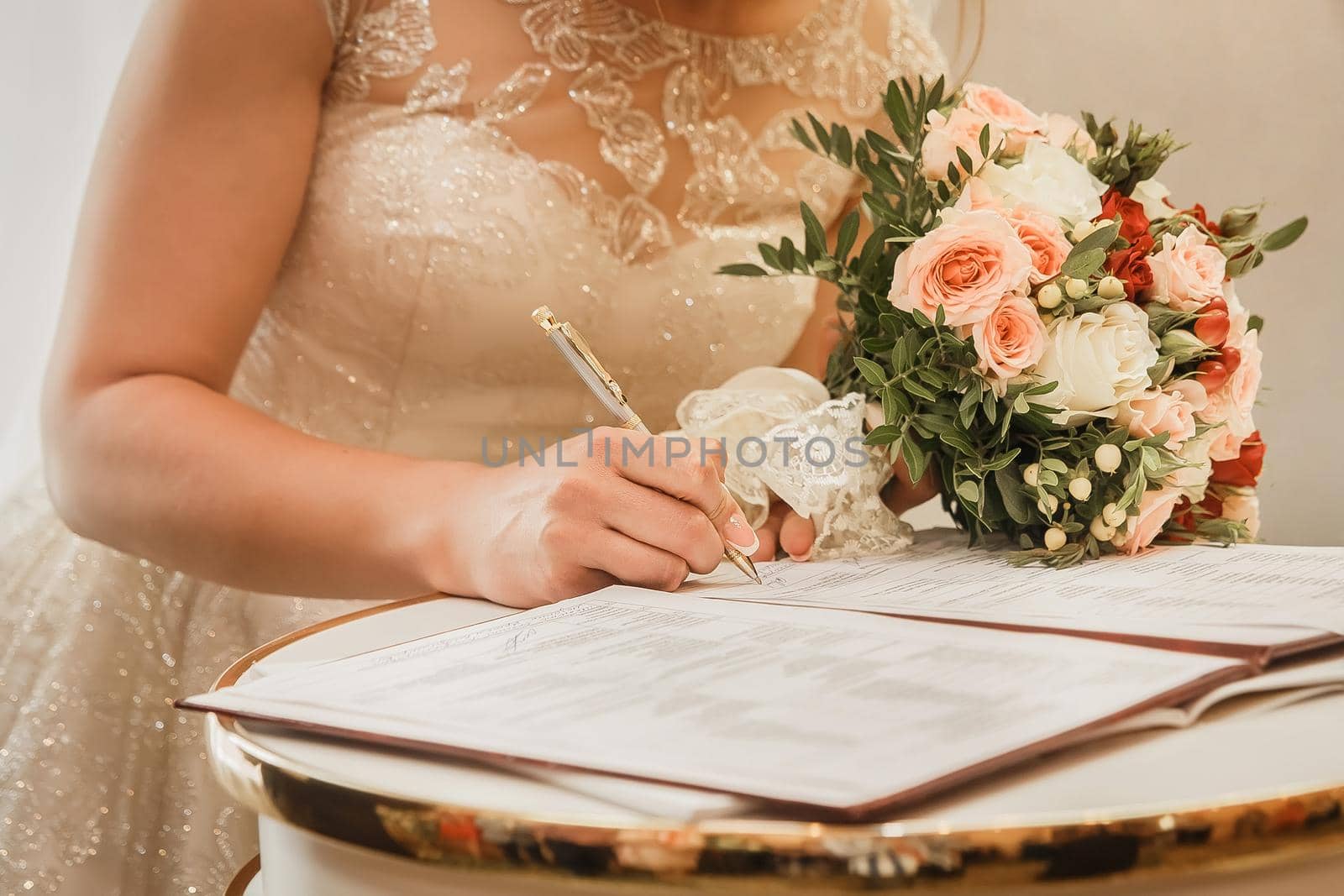 Bride's hand puts signature pen on consent to marry at wedding close-up.