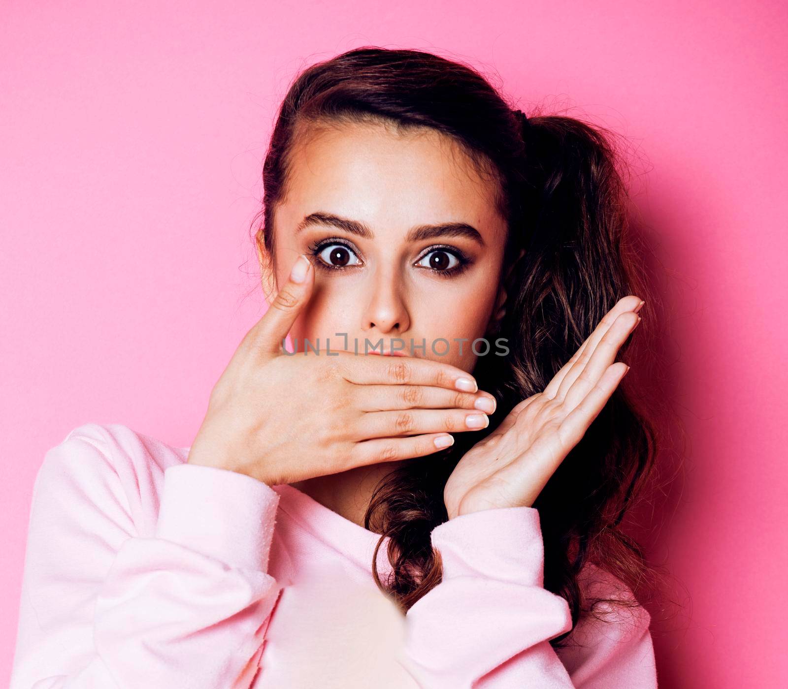 young pretty teenage girl emotional posing on pink background, fashion lifestyle people concept closeup copyspace