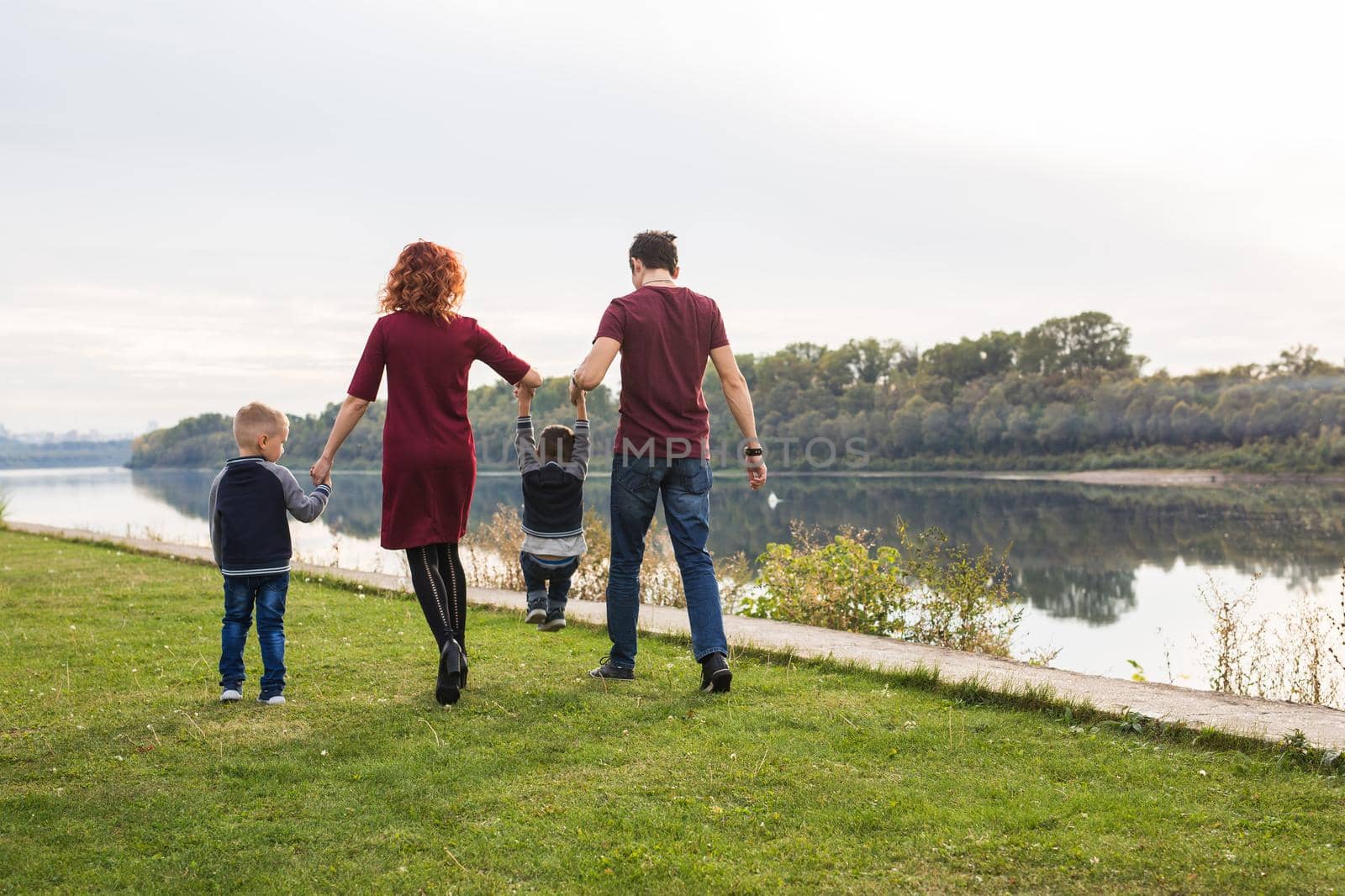 Parent, childhood and nature concept - Family playing with two sons by the water.