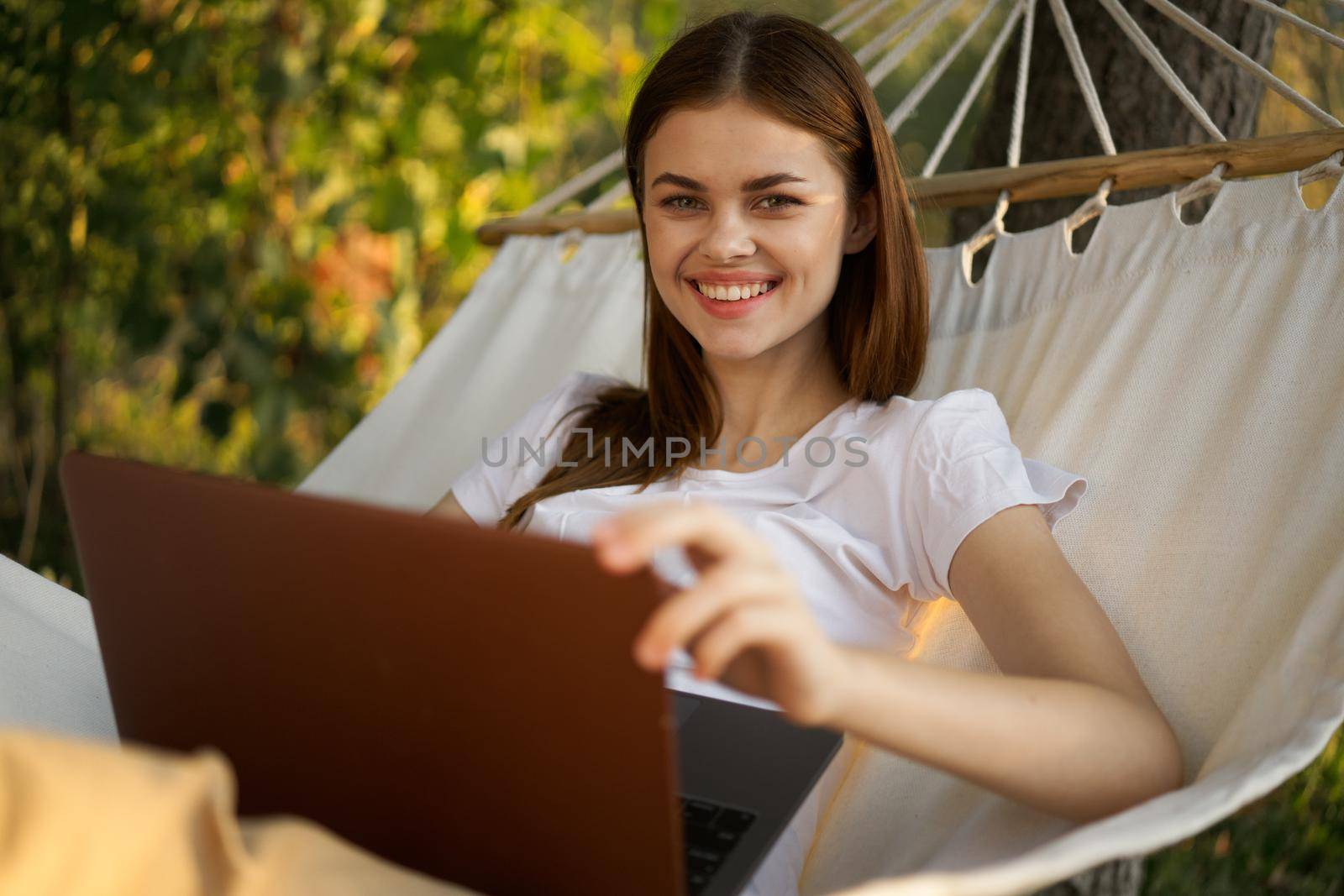 woman with laptop lies in hammock freelance travel. High quality photo