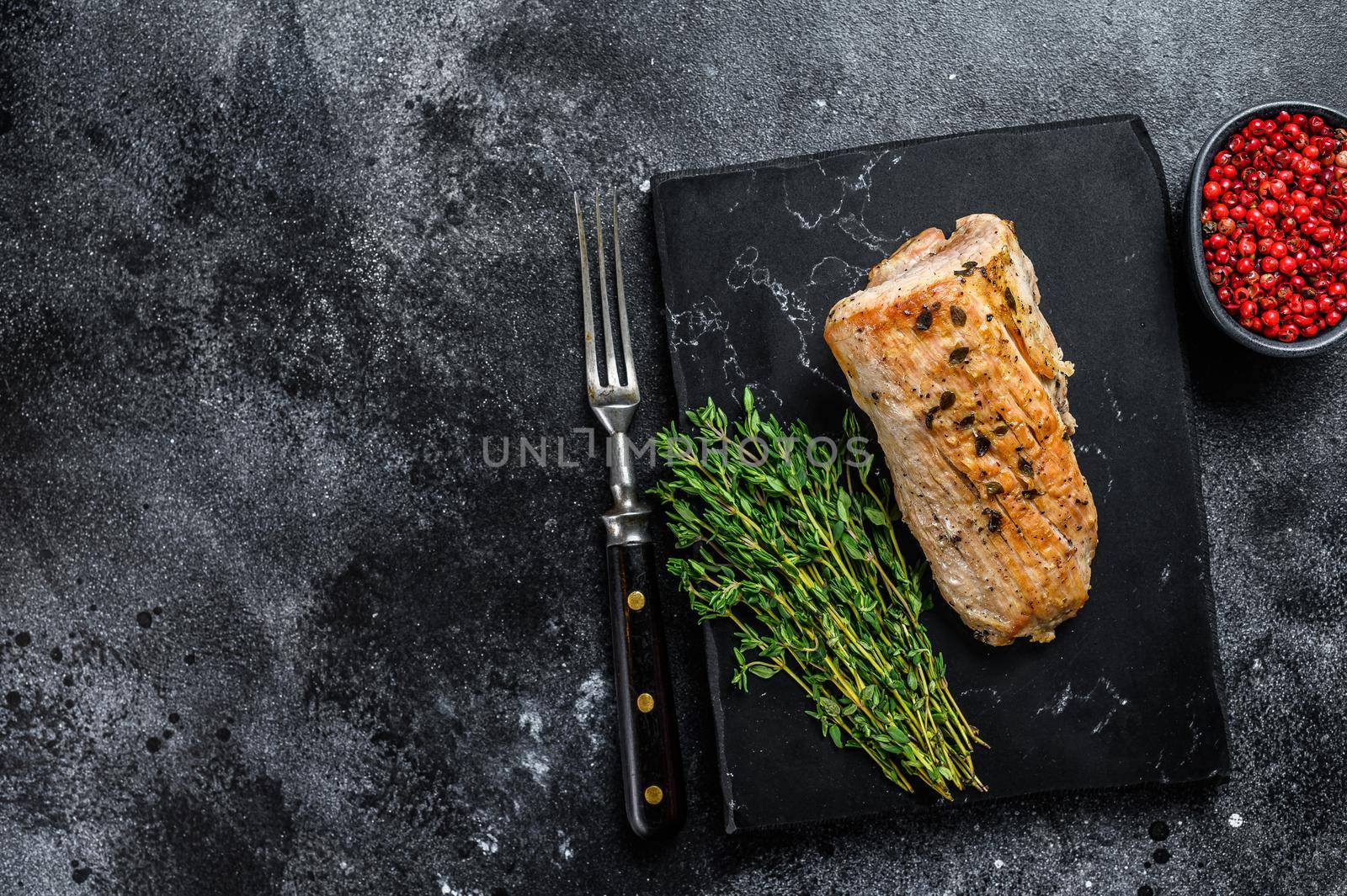 Whole barbecue baked pork tenderloin. Black background. Top view. Copy space by Composter