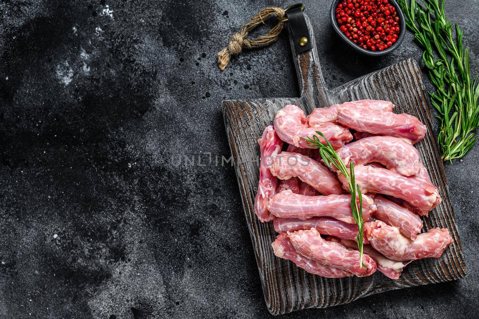 Raw chicken neck meat on a cutting board. Black background. Top view. Copy space by Composter