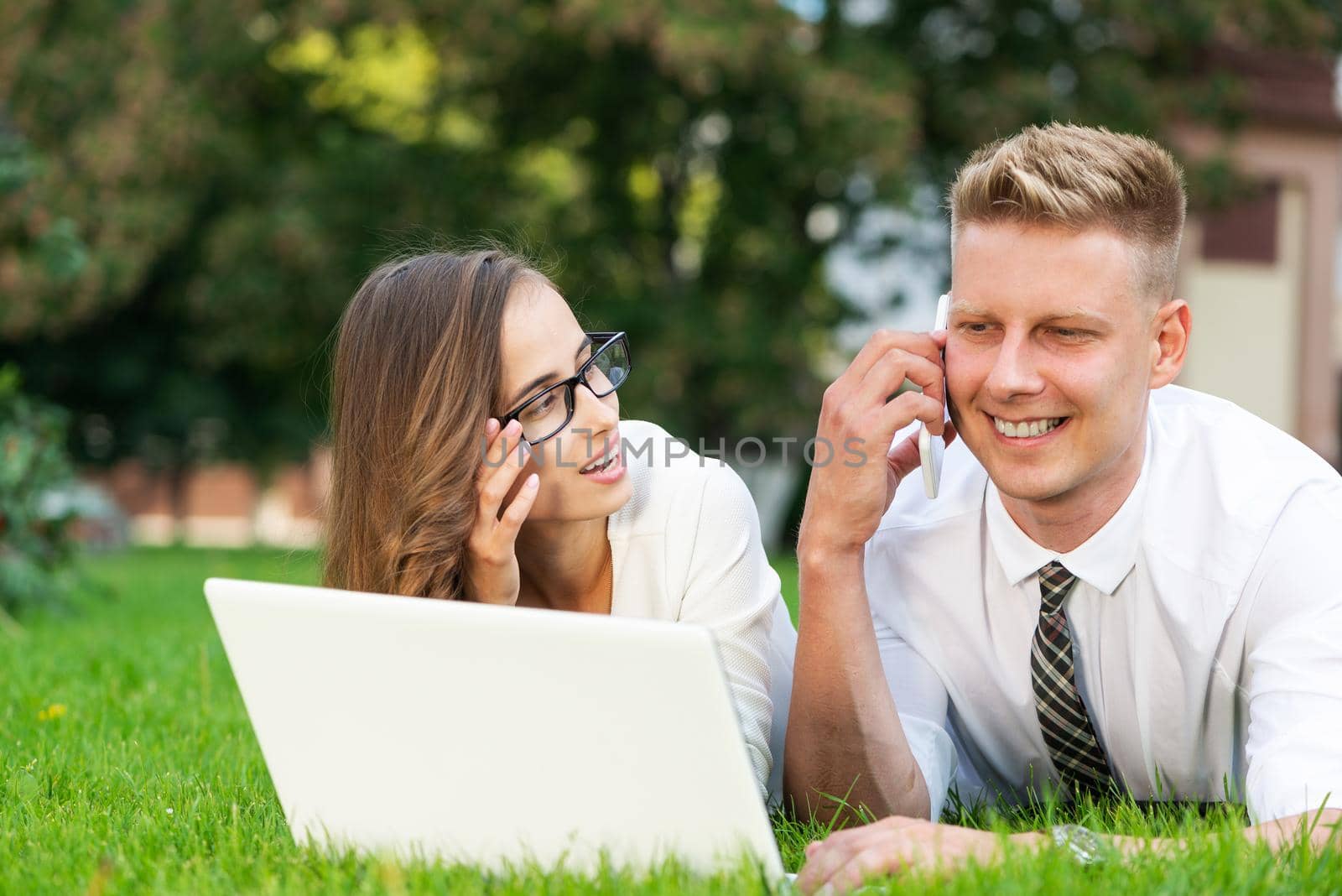 businessman and businesswoman with a laptop in a city park by adam121