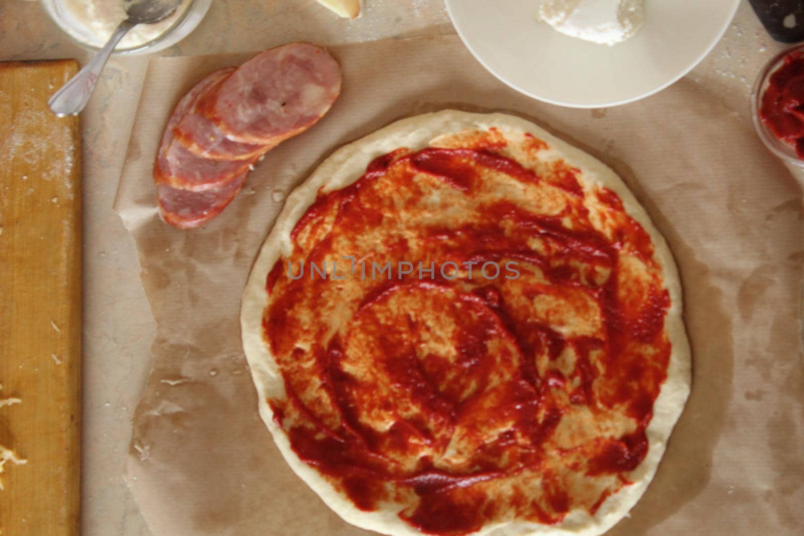 step-by-step instructions for cooking pizza. Step 1. Roll the dough onto the dough and spread the tomato sauce. Dough with red tomato sauce next to sio sauce. top side view by Shoba