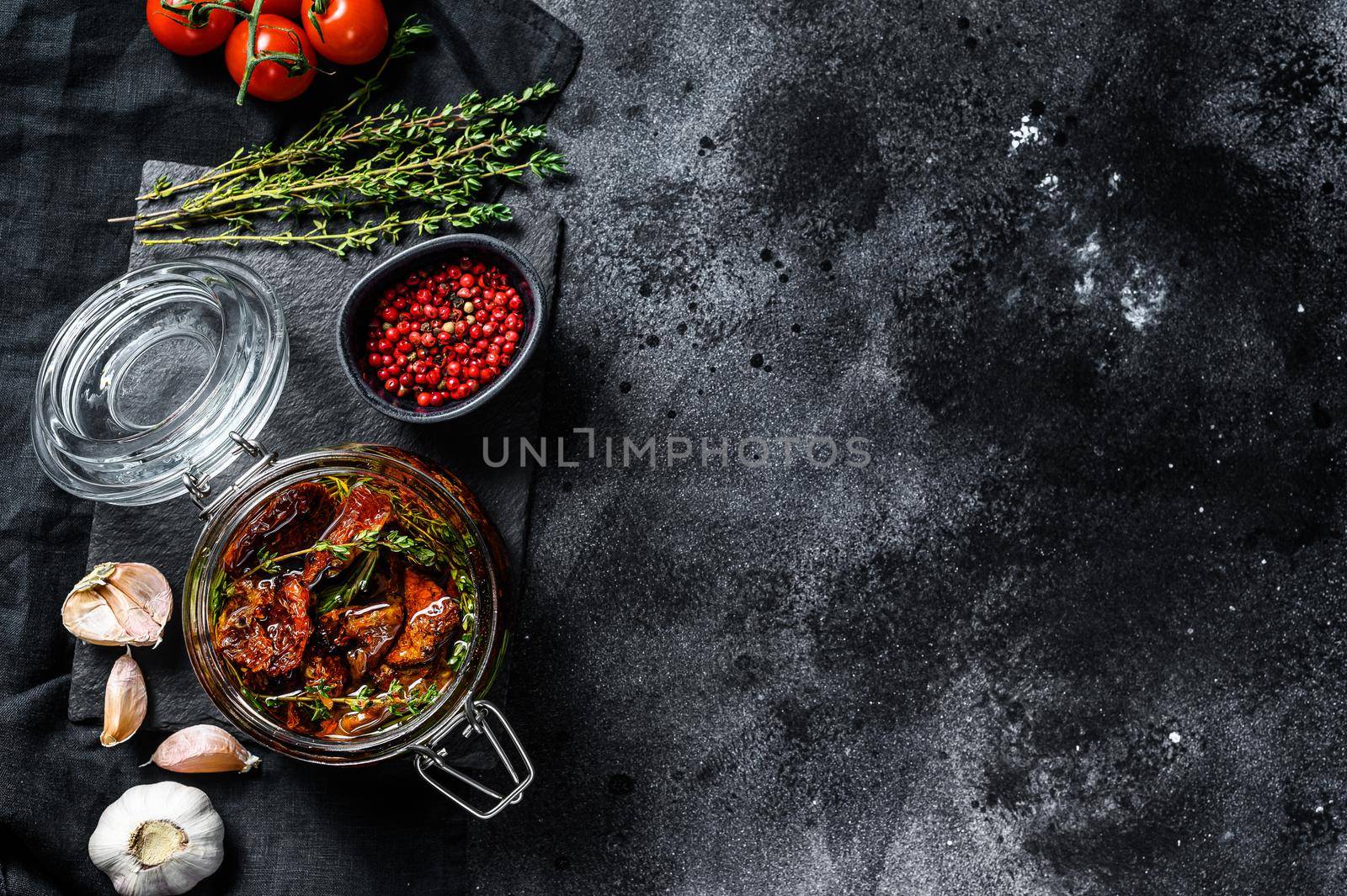 Recipe for cooking dried tomatoes in olive oil with spices and herbs. Black background. Top view. Copy space.