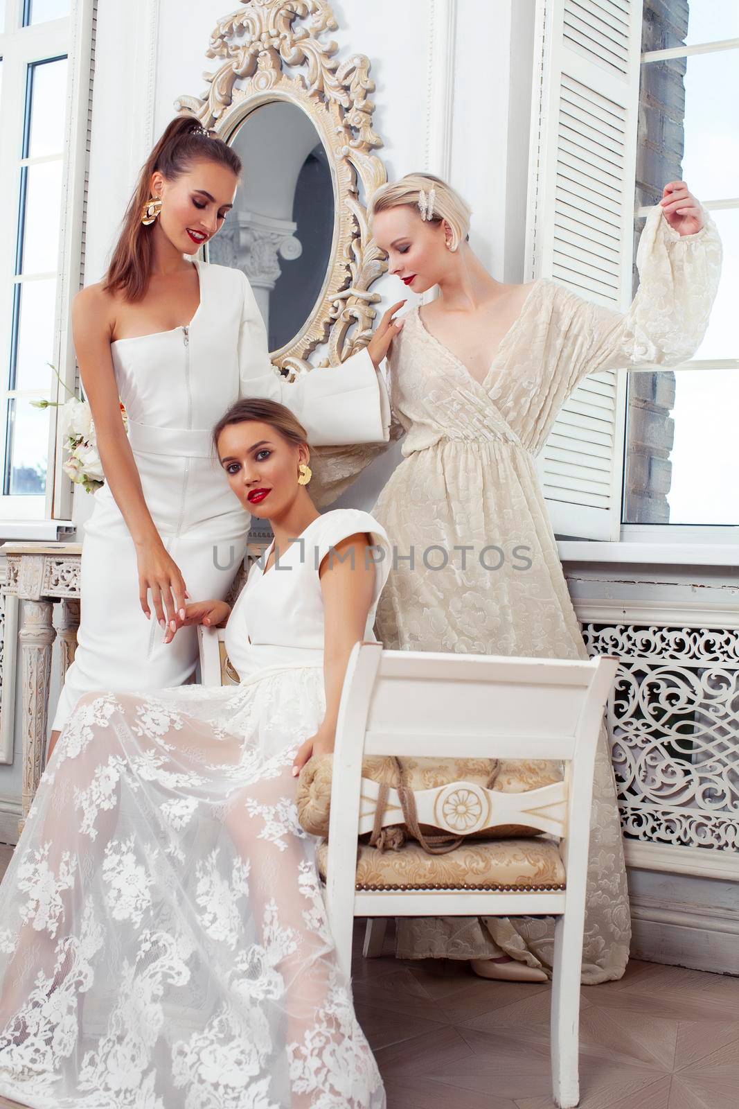 three young pretty lady in white lace fashion style dress posing in rich interior of royal hotel room, luxury lifestyle people concept, bride on wedding day by JordanJ