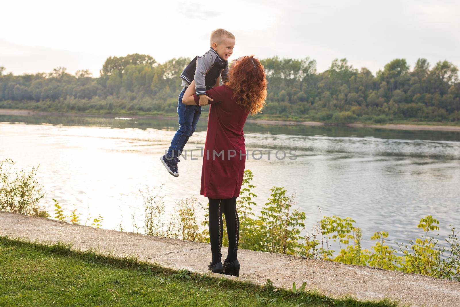 Motherhood and children concept - young mother with son in her arms near the river by Satura86