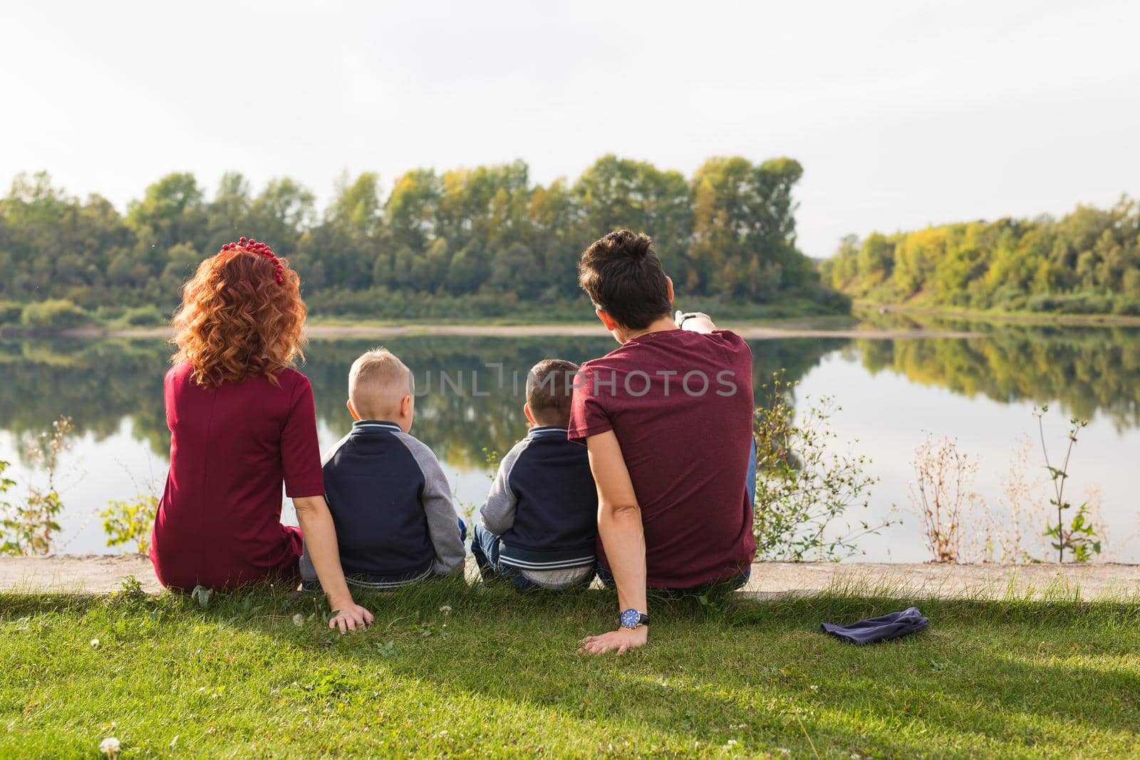 Parenthood, nature, people concept - family with two sons sitting near the lake by Satura86