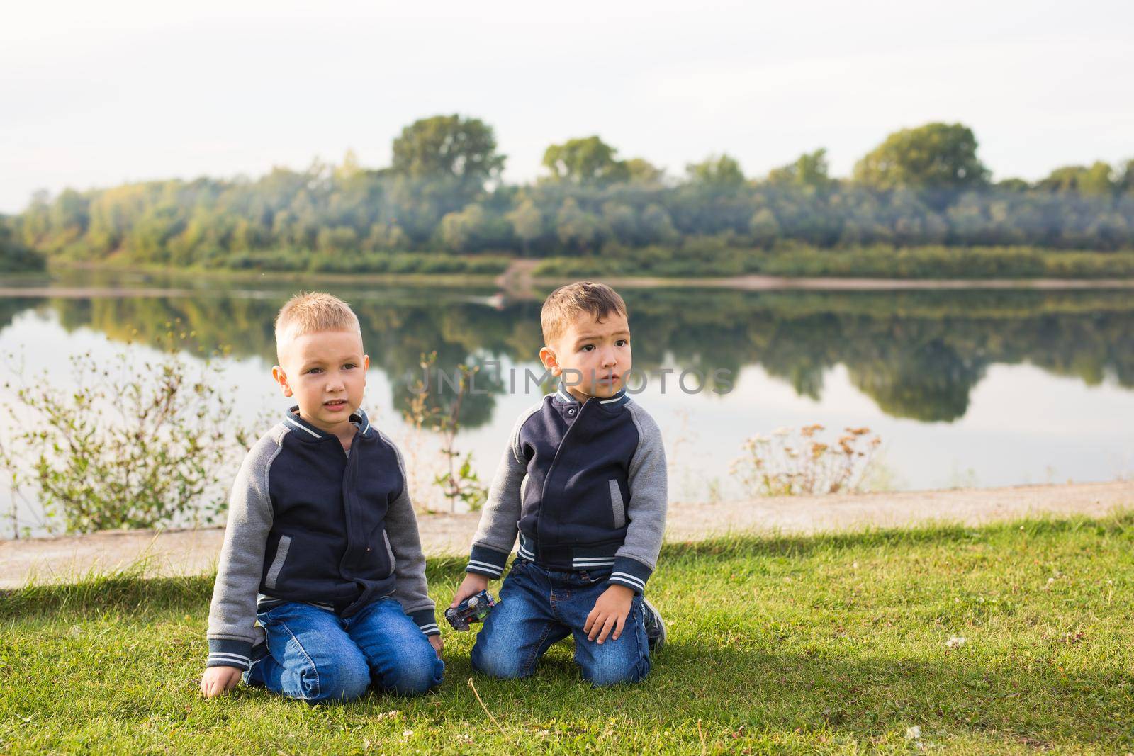 Children and nature concept - Two brothers sitting on the grass over nature background by Satura86