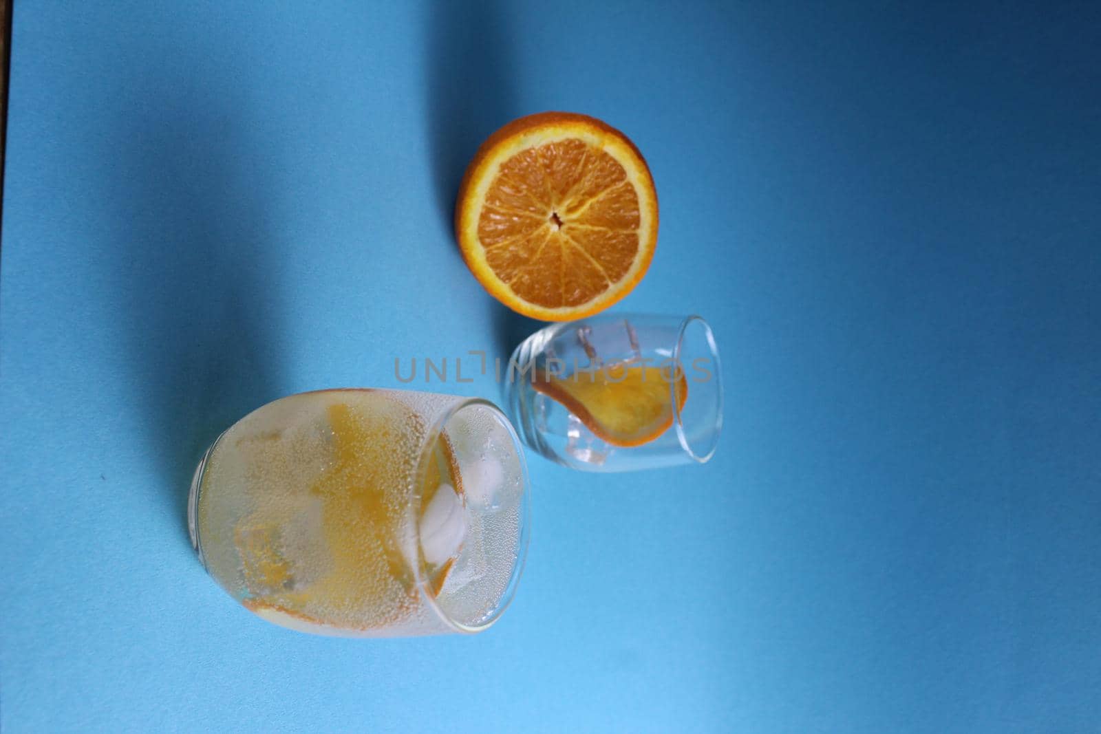 Step-by-step making of lemonade. Step 2. Pour the fruit orange with soda water. A glass of lemonade orange on a blue background with a place for text . close-up by Shoba