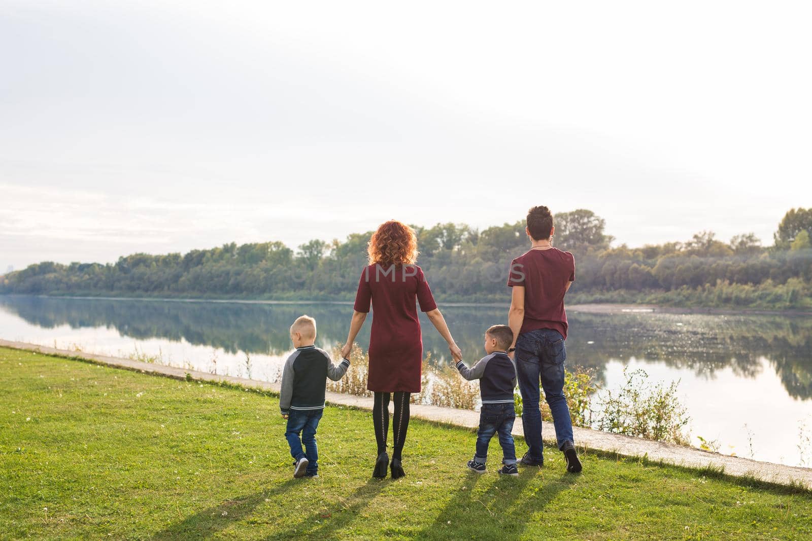 Parenthood and nature concept -Family of mother and father with two boys twins kids in a park at summer by a river at sunny day by Satura86