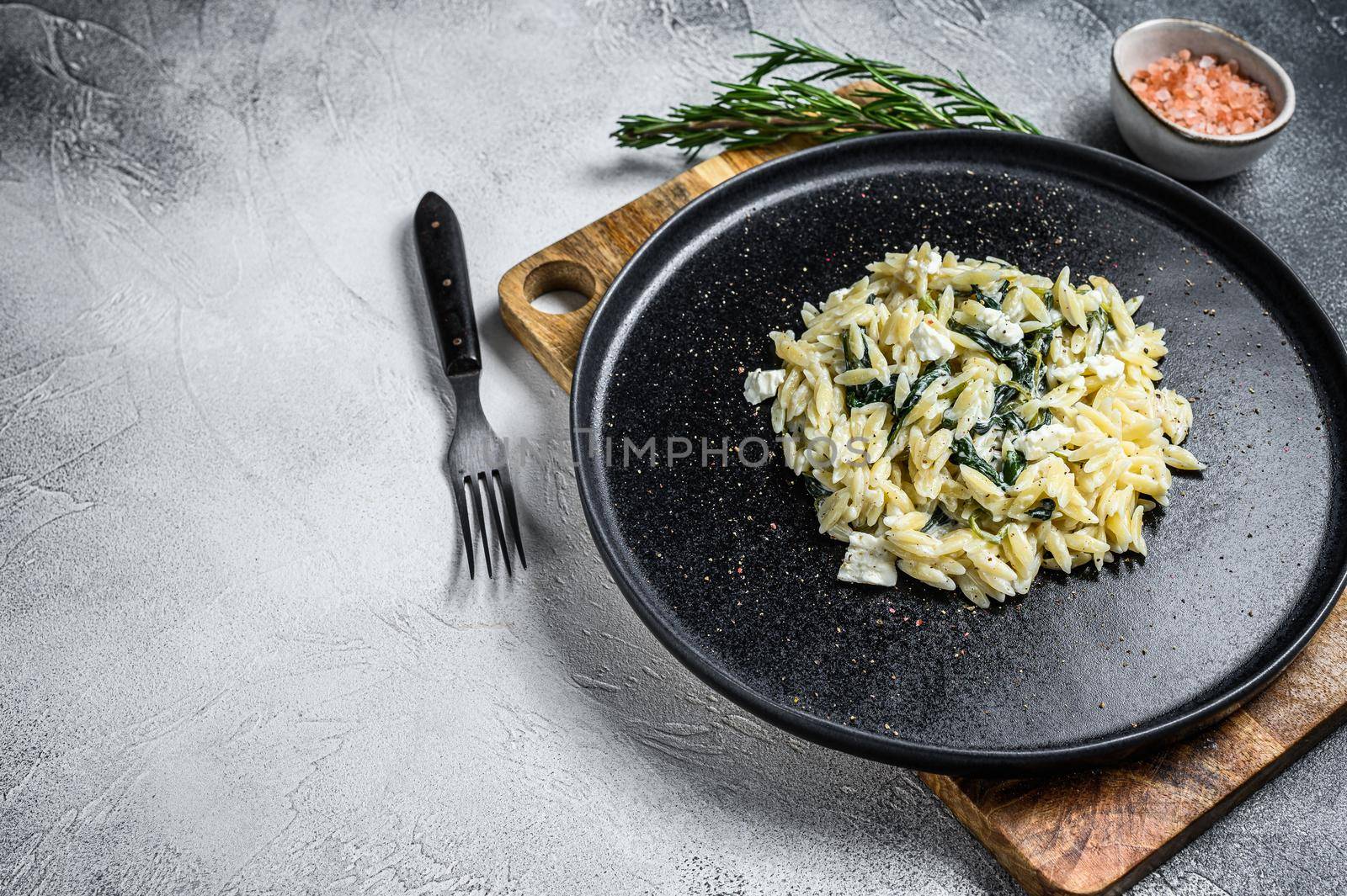 Spinach and Feta orzo pasta on a plate. White background. Top view. Copy space by Composter
