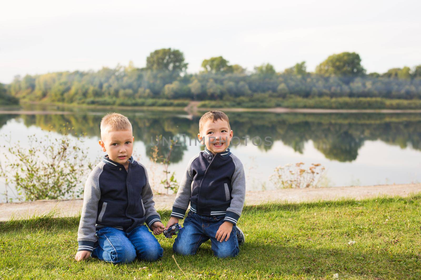 Children and nature concept - Two brothers sitting on the grass over nature background by Satura86