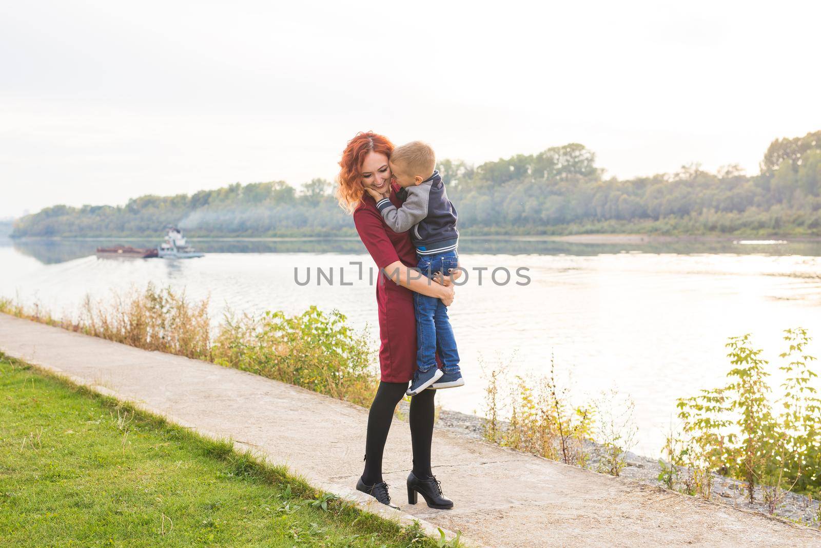 Family and children concept - Redhead woman holding her son over water background by Satura86