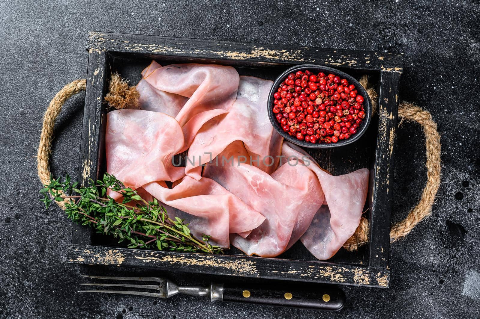 Thin sliced Smoked pork ham in wooden tray. Black background. Top view by Composter