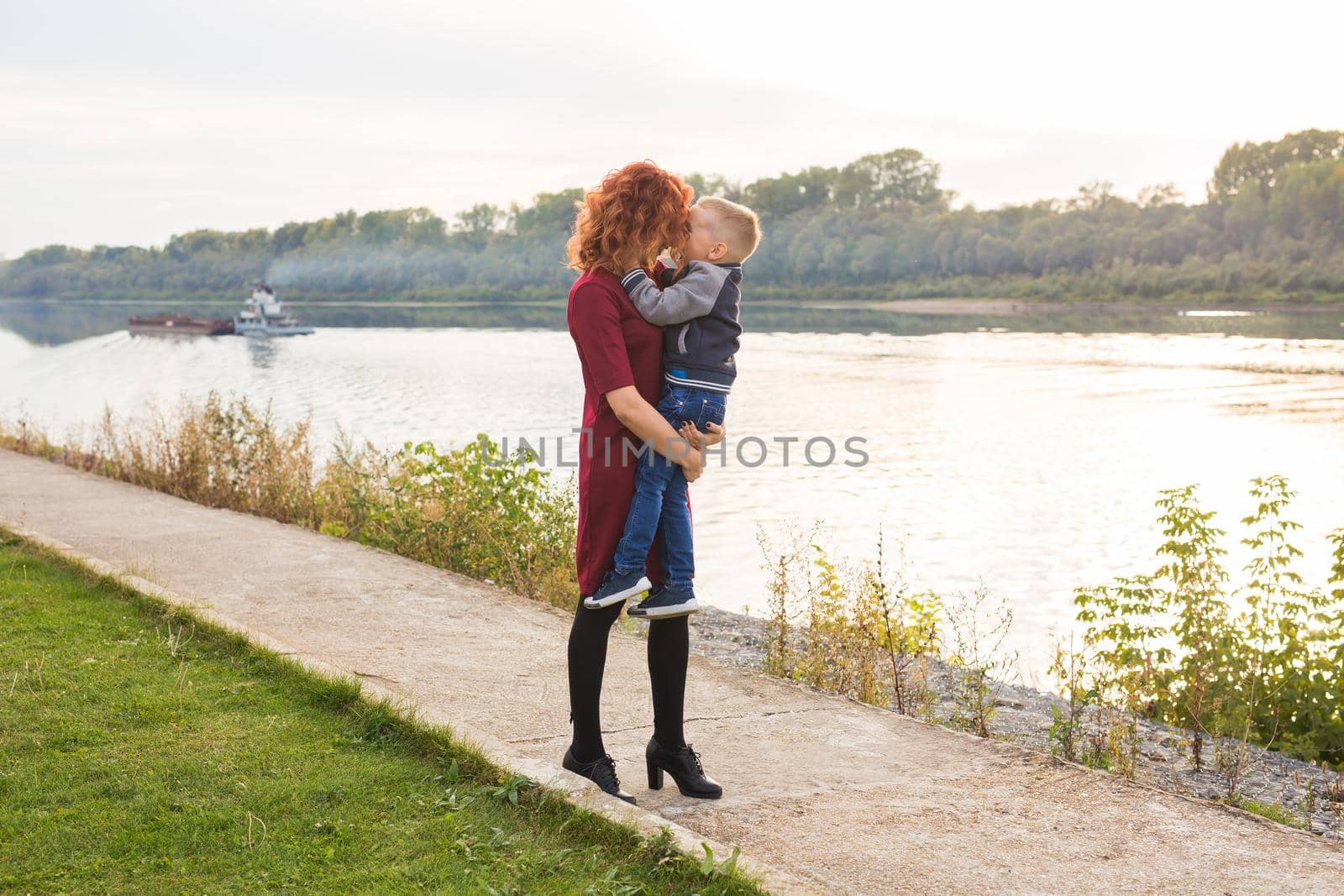 Motherhood and children concept - young mother with son in her arms near the river by Satura86