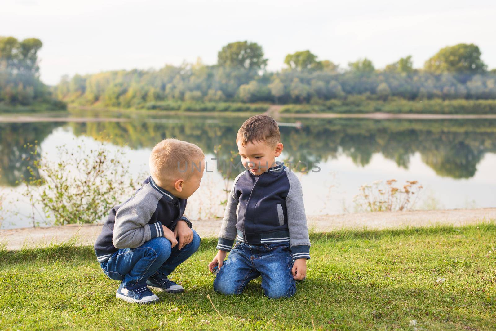 Children and nature concept - Two brothers sitting on the grass over nature background.