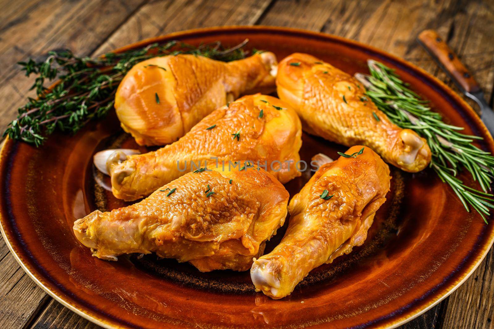 Fresh Smoked chicken drumsticks on a rustic plate with herbs. wooden background. Top view.