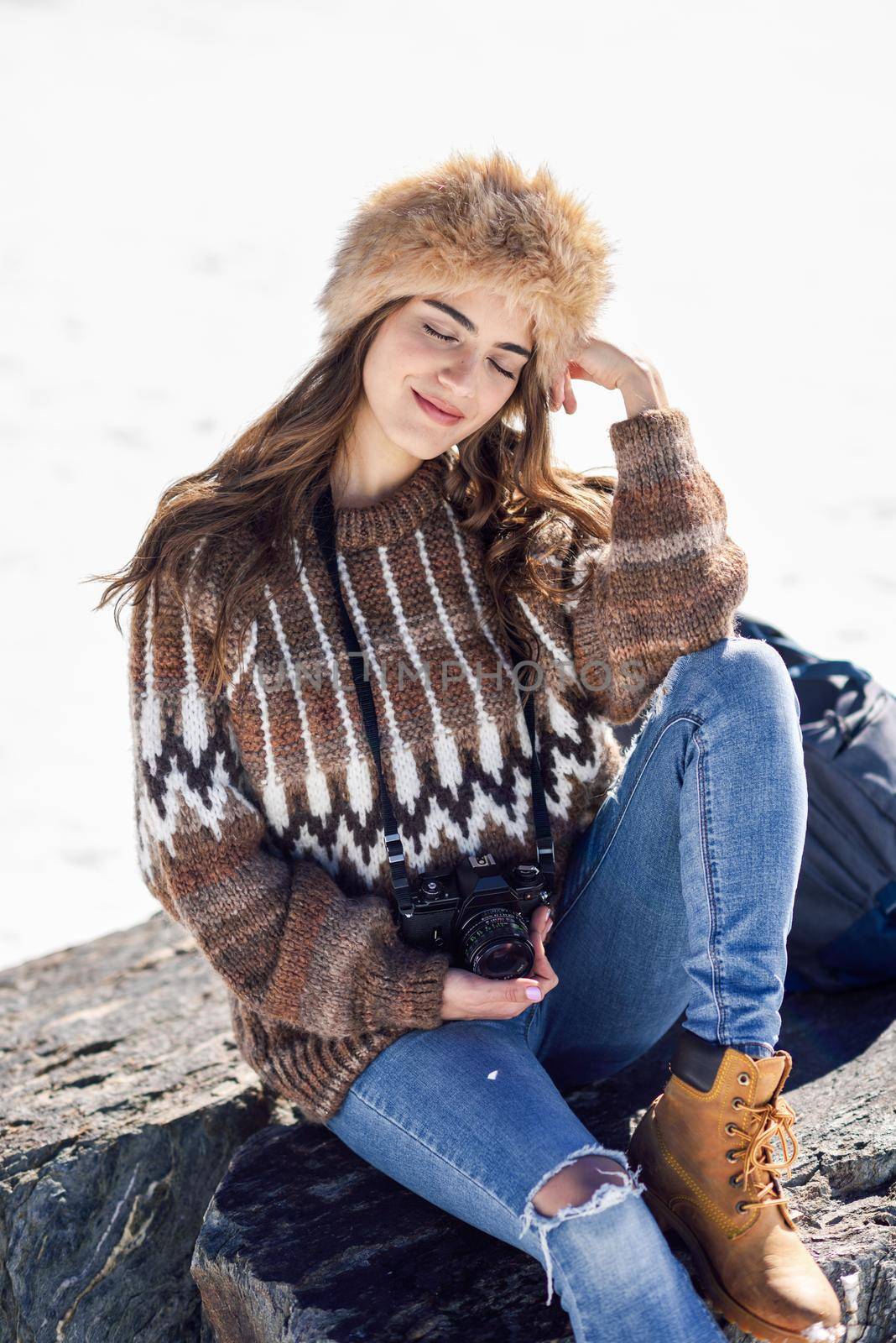 Young woman taking photographs in the snowy mountains in winter, in Sierra Nevada, Granada, Spain. Female wearing winter clothes.