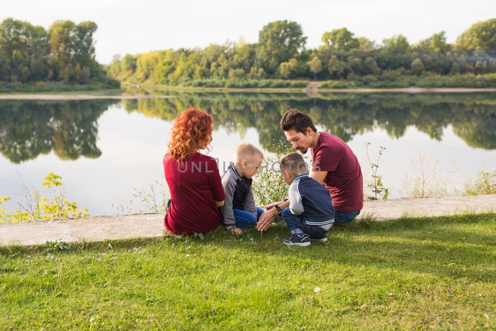 Parenthood, nature, people concept - family with two sons sitting near the lake by Satura86