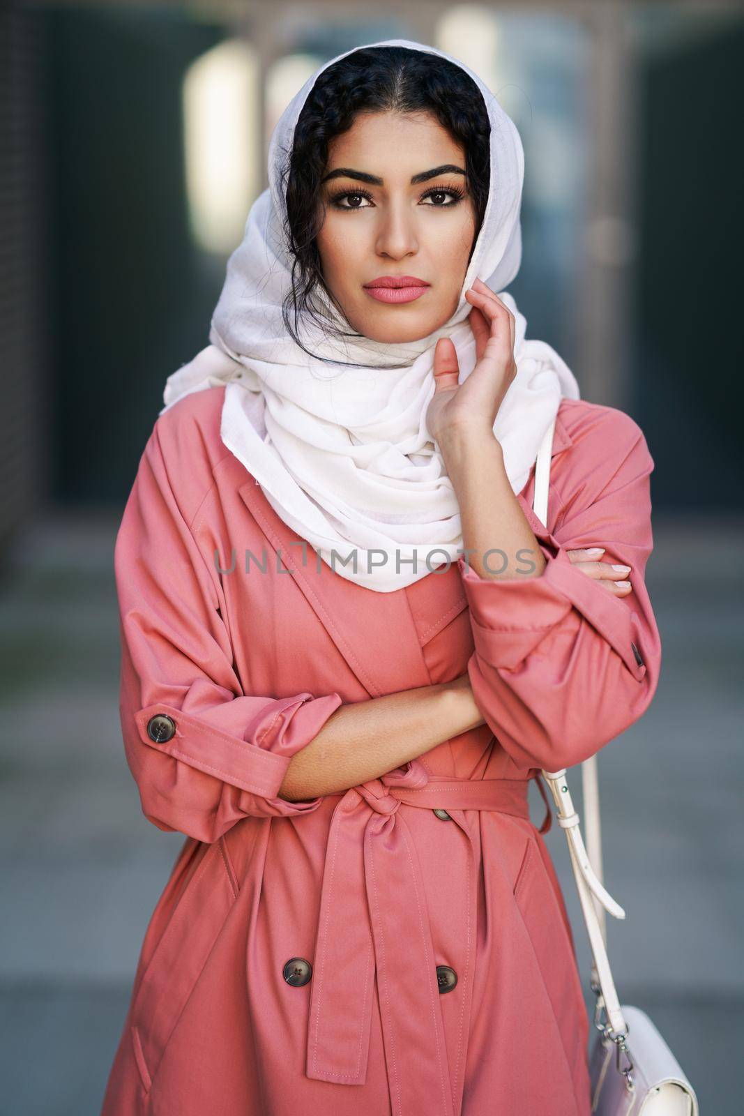Young Muslim woman wearing hijab headscarf walking in the city center. Arab female in urban background
