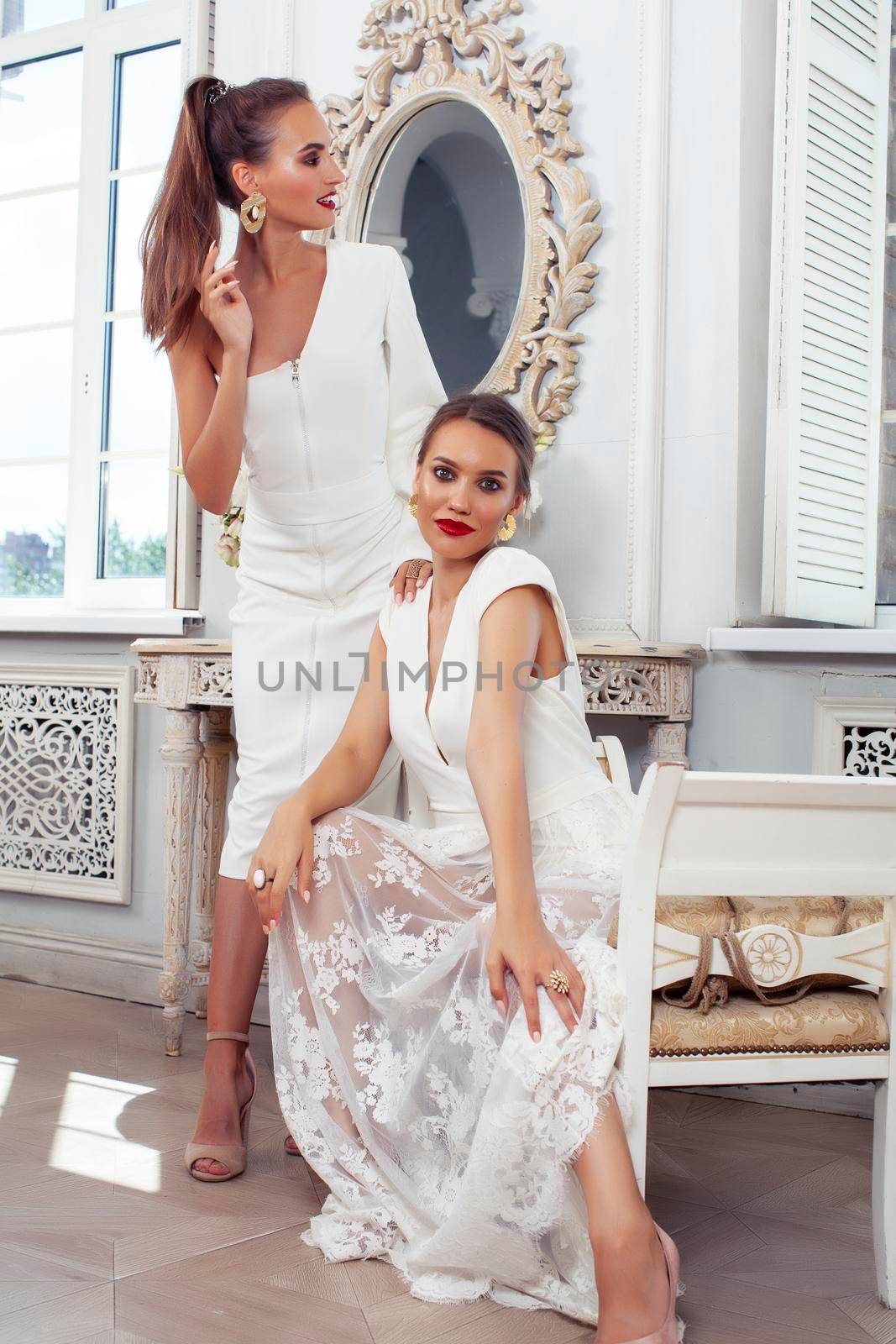 two young pretty lady in white lace fashion style dress posing in rich interior of royal hotel room, luxury lifestyle people concept, bride on wedding day by JordanJ