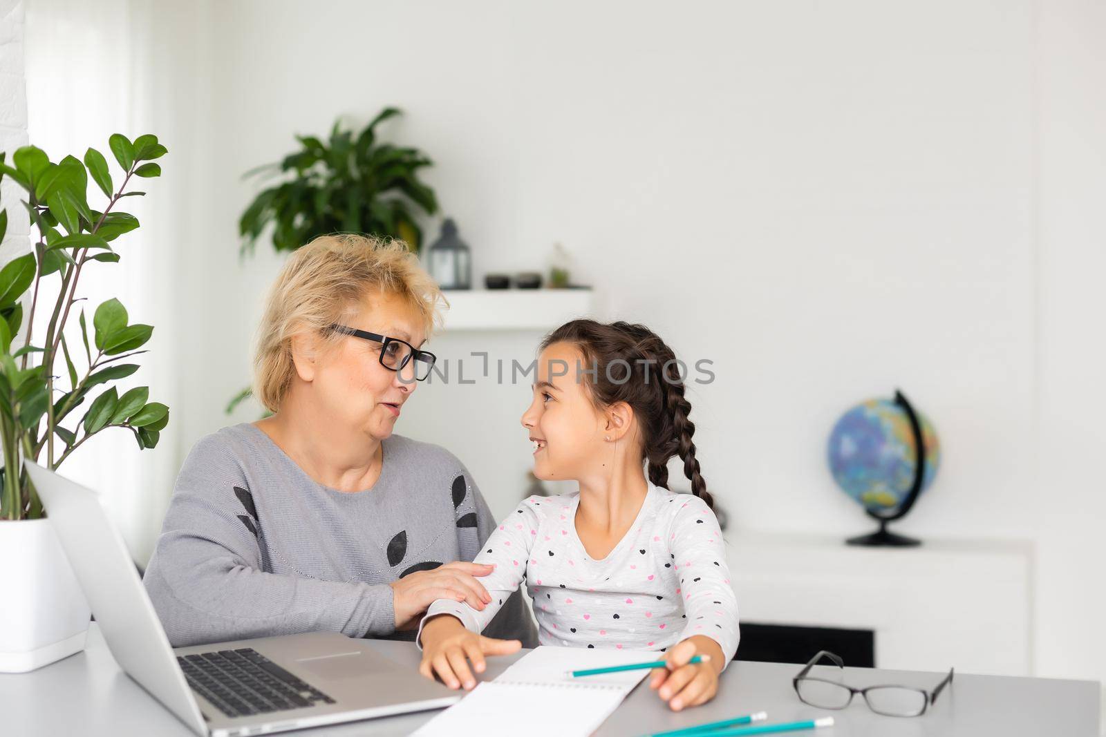 Helpful granny. Helpful loving granny assisting her cute granddaughter making homework