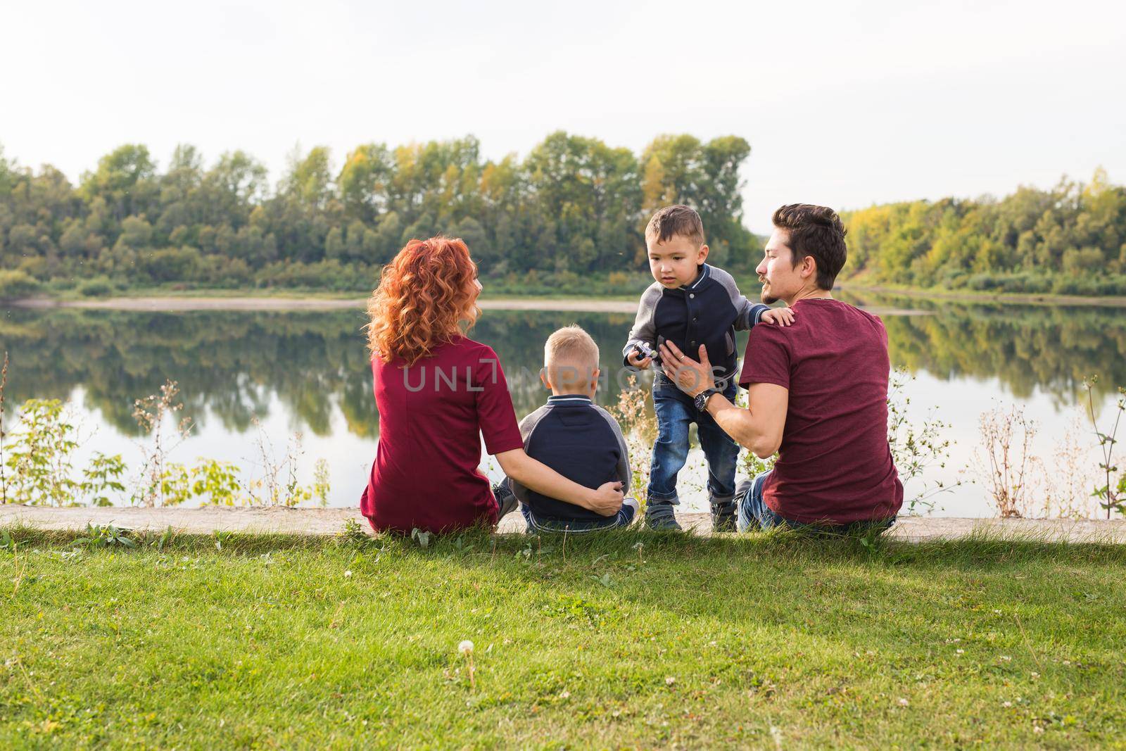 Childhood and nature concept - Family with little sons sitting on the green grass by Satura86