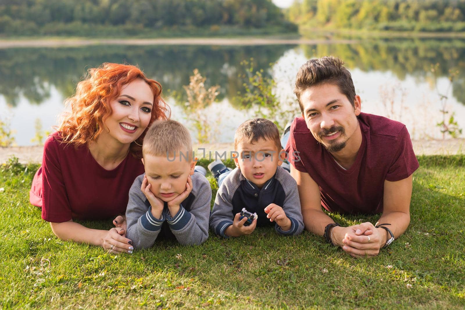 Children, parenthood and nature concept - Big family lying on the grass.