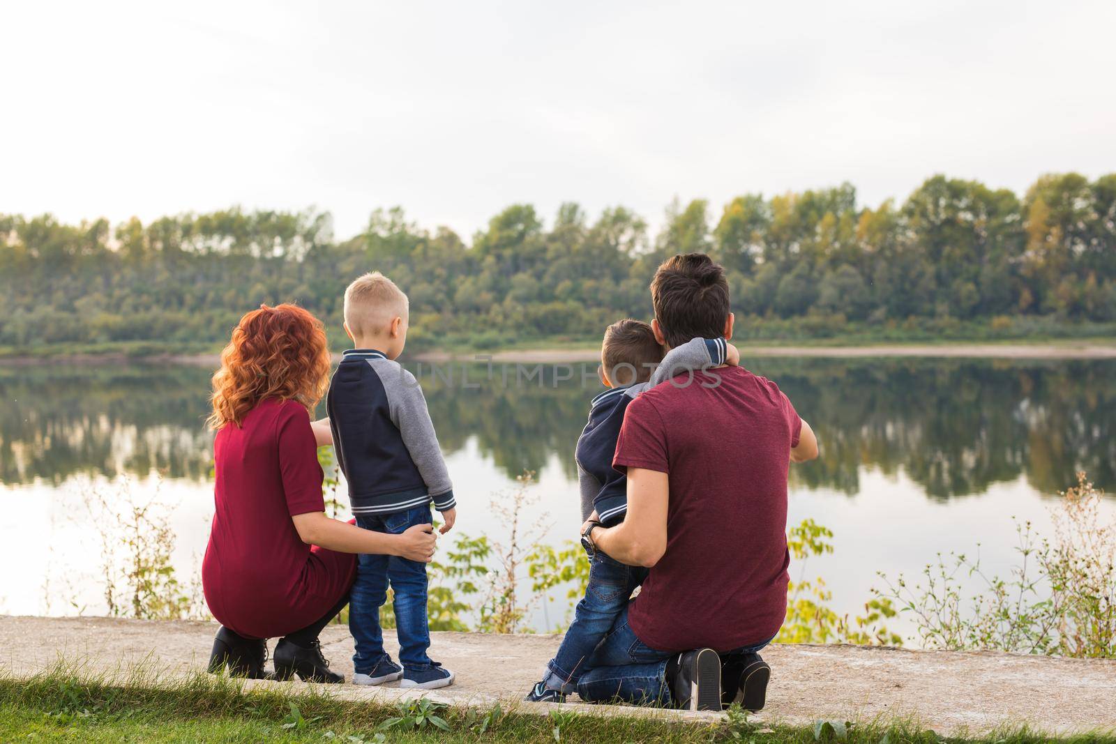 Parenthood, childhood and family concept - Parents and two male children walking at the park and looking on something, back view by Satura86