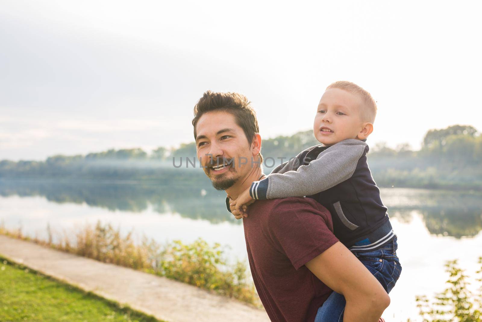 Family, childhood, fatherhood concept - Father piggyback his little son outside by Satura86