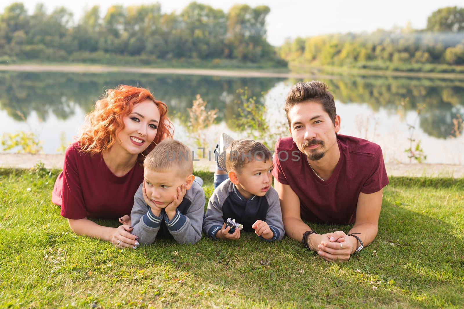 Children, parenthood and nature concept - Big family lying on the grass.